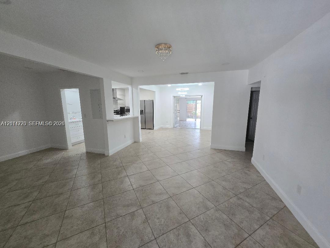 Open-concept interior featuring large-format neutral floor tile, recessed lighting, breakfast bar, and glass-paneled exterior door Open-concept interior featuring large-format neutral floor tile, recessed lighting, breakfast bar, and glass-paneled exterior door