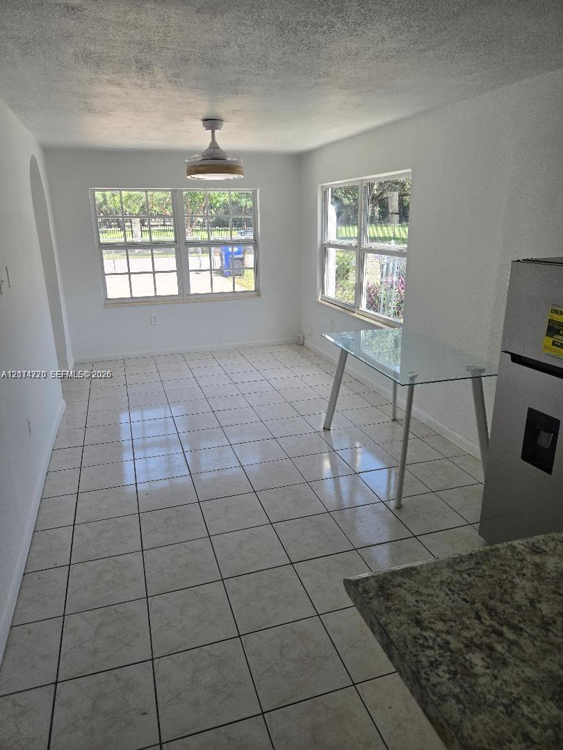 Neutral tile flooring, dual multi-pane windows, and a central ceiling fan