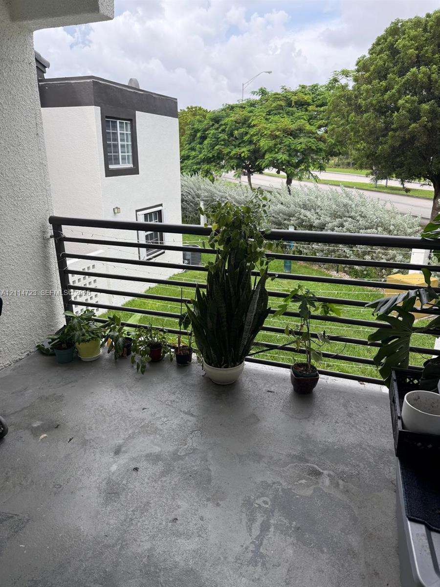 Covered balcony featuring concrete flooring and a horizontal metal railing Covered balcony featuring concrete flooring and a horizontal metal railing