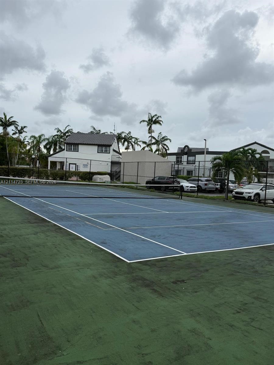 Tennis court featuring a blue surface with white boundary markings and a perimeter chain-link fence