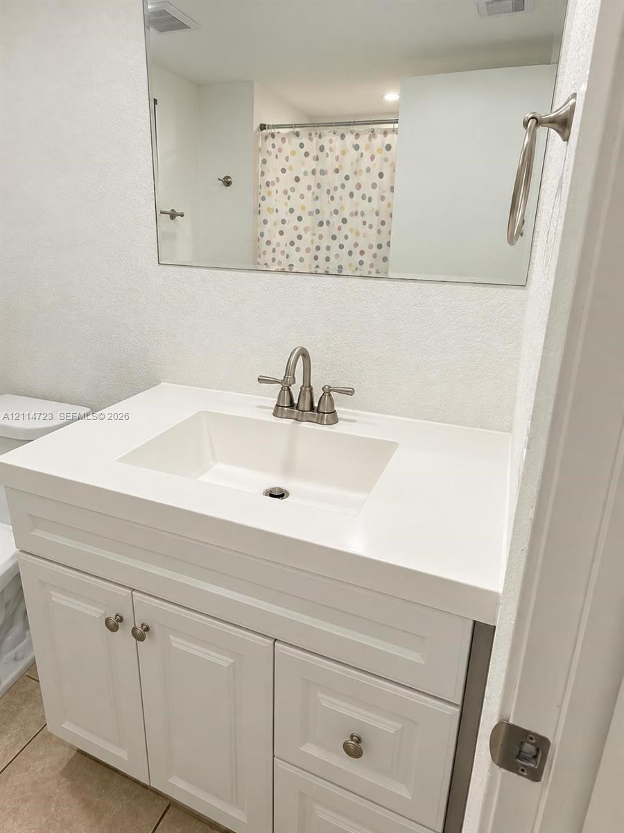 White vanity featuring a solid-surface countertop with an integrated rectangular sink and brushed nickel hardware White vanity featuring a solid-surface countertop with an integrated rectangular sink and brushed nickel hardware