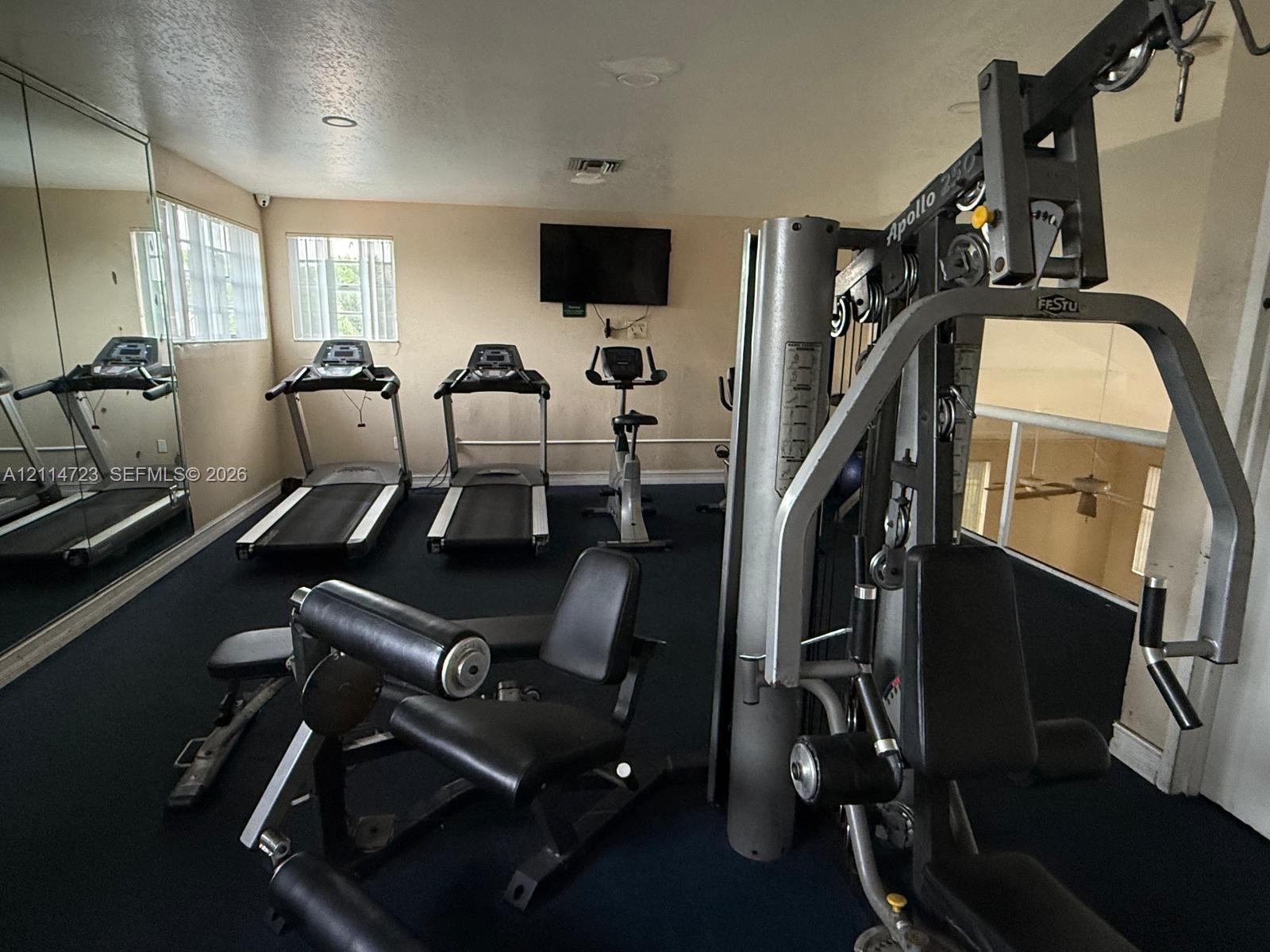 Fitness space featuring a wall-to-wall mirror, recessed lighting, and carpeted flooring