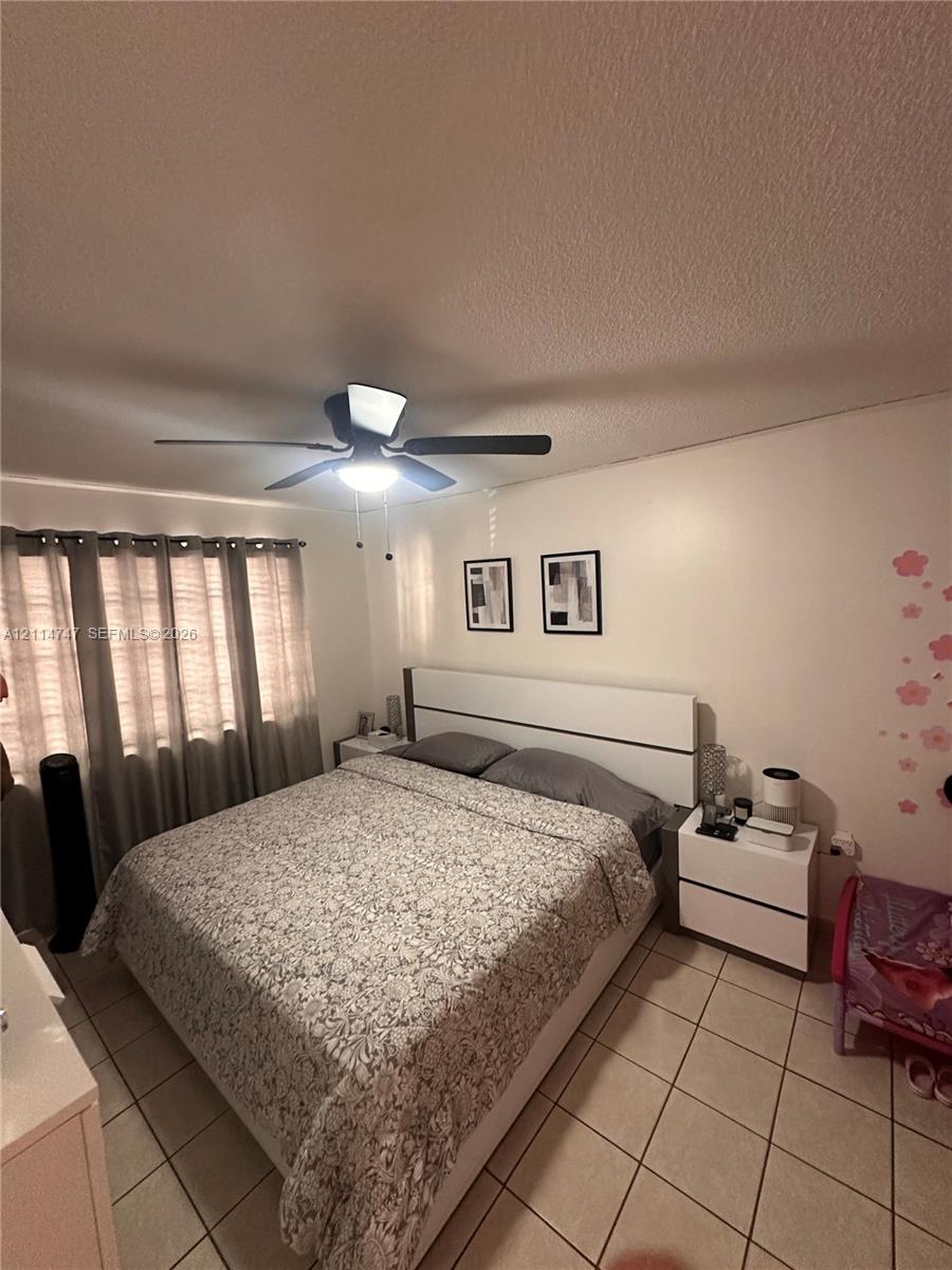 Ceramic tile flooring, neutral wall tones, and a ceiling-mounted light fixture with integrated fan