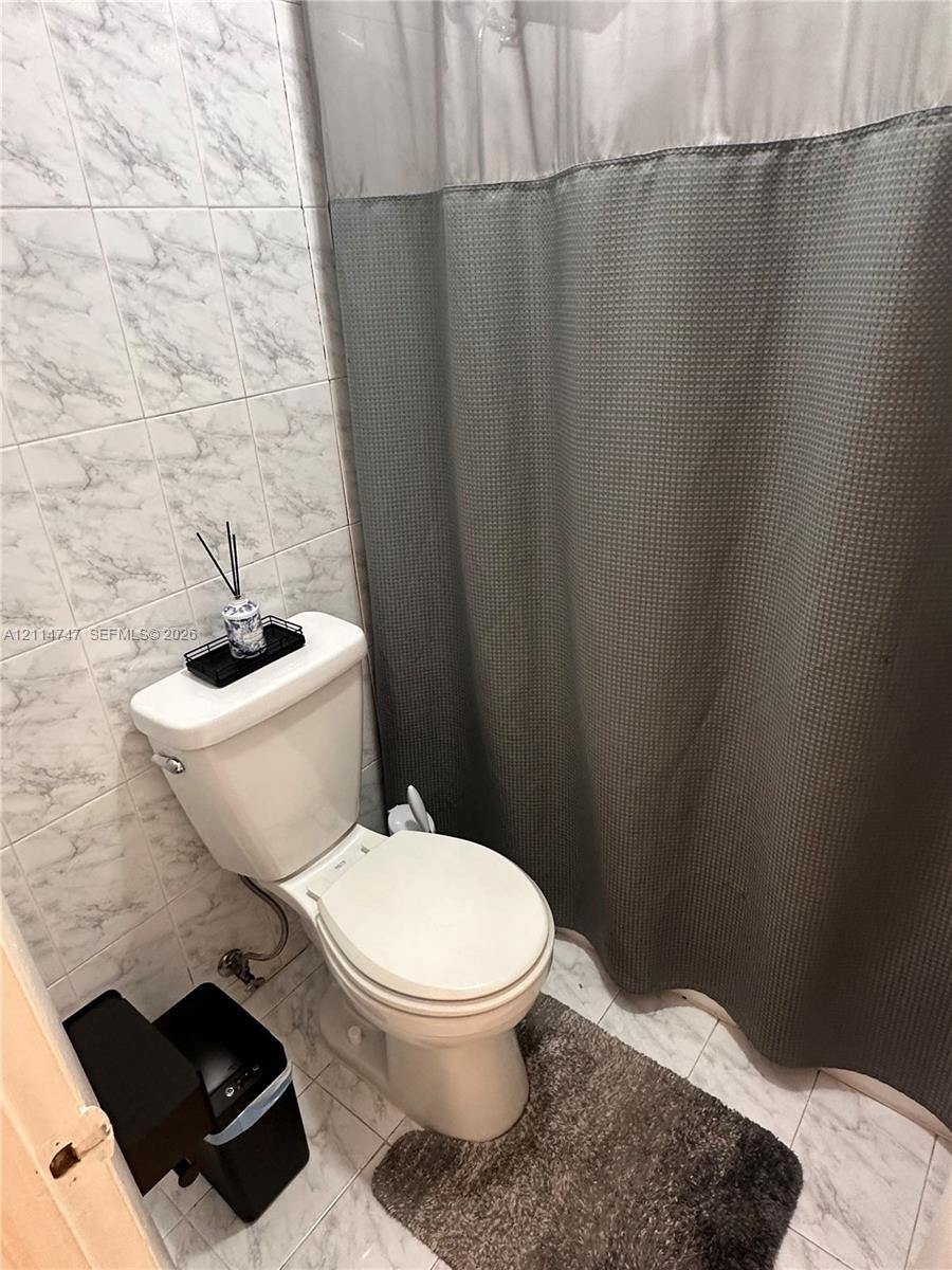 Bathroom featuring light-toned stone-patterned wall and floor tiling