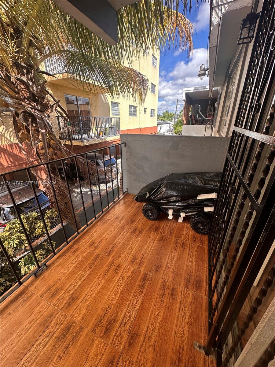 Balcony featuring wood-finish flooring, black metal railings, and attached exterior lighting