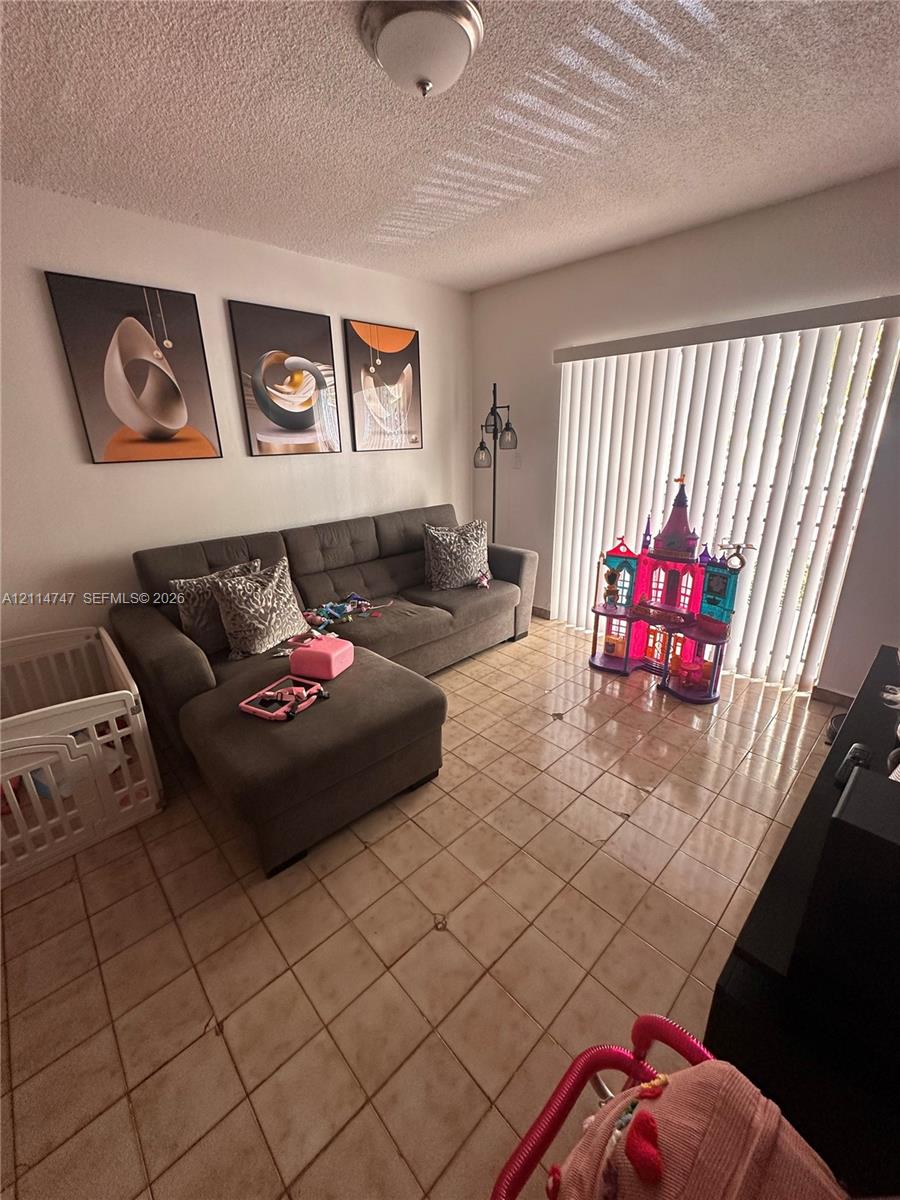 Interior space featuring tile flooring, ceiling-mounted light fixture, and floor-to-ceiling vertical blinds