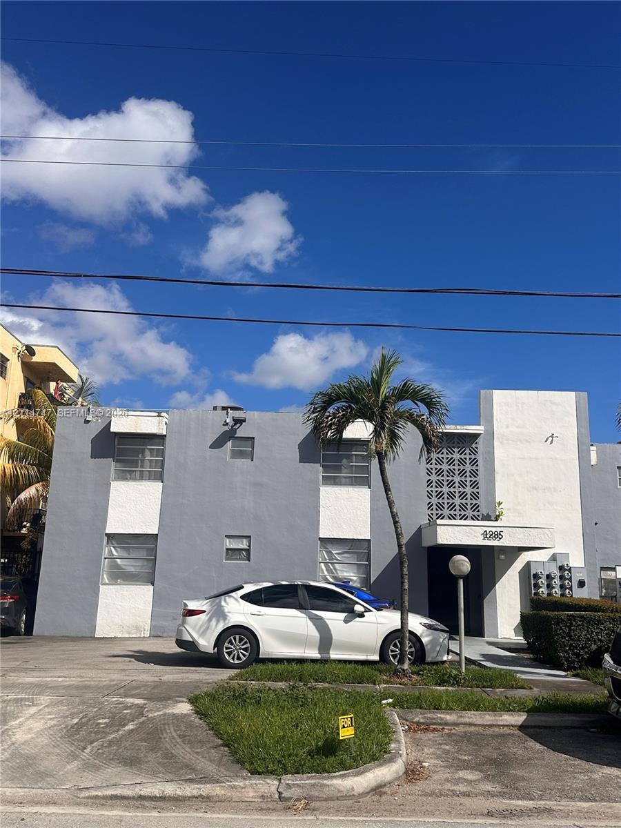 Mid-century architectural exterior featuring a two-story concrete facade with decorative geometric breeze block detailing and a concrete entrance overhang