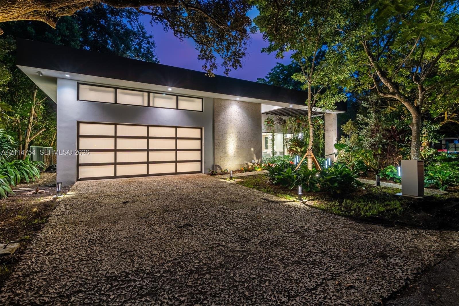 Aerial perspective featuring a rectangular swimming pool, central open-air courtyard with stone landscaping, multi-section metal roofing, and mature perimeter trees