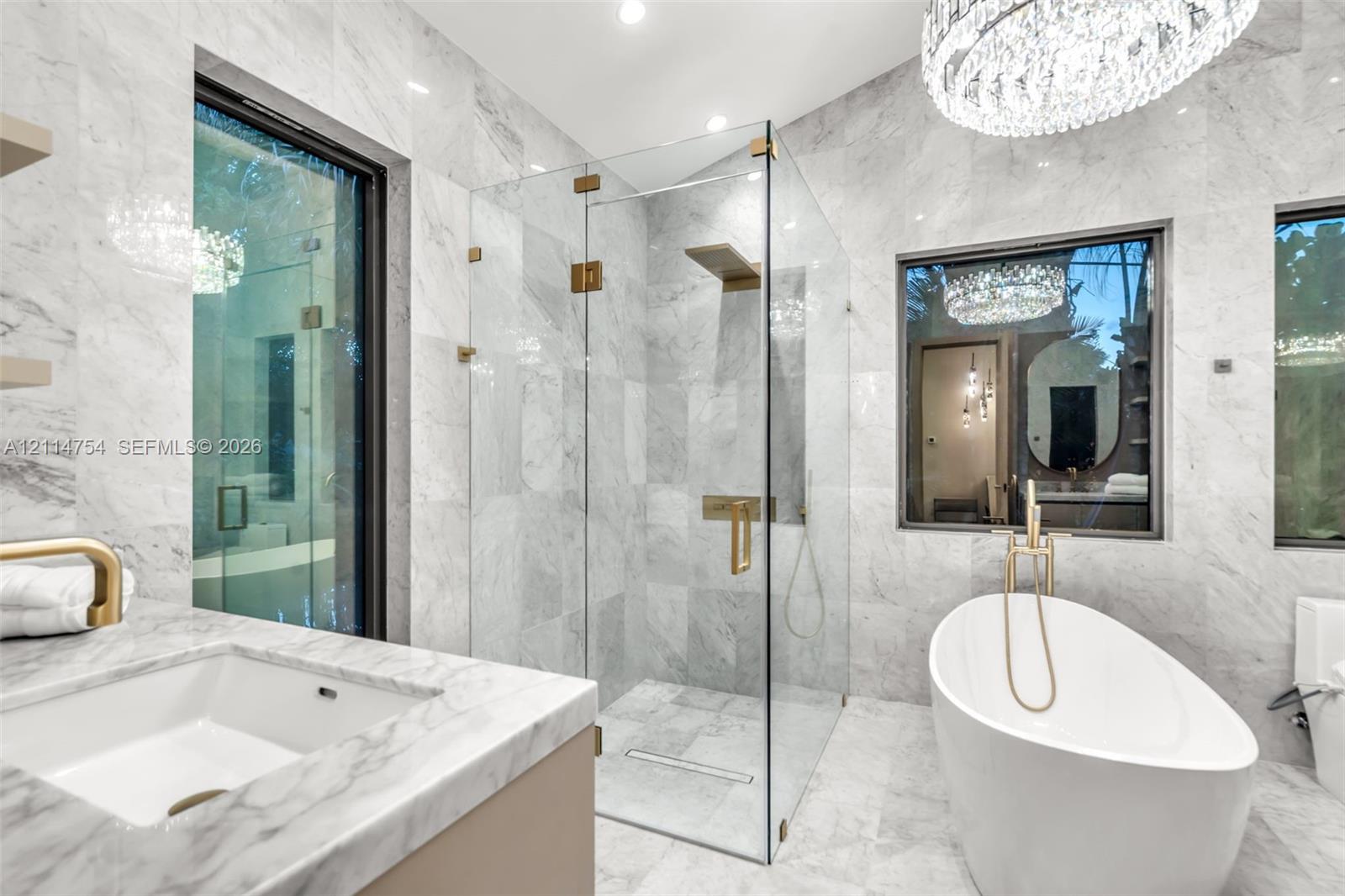 Vaulted ceilings, large-format tile flooring, floor-to-ceiling glass sliding doors, modern circular chandelier, and recessed lighting