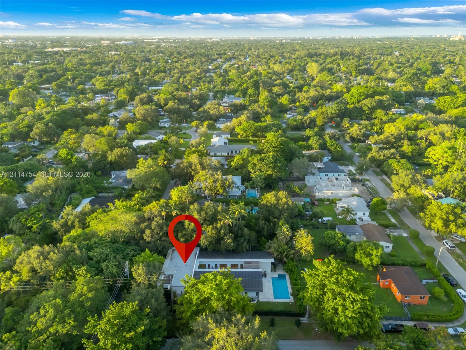 Aerial perspective showcasing a parcel characterized by dense, mature tree canopy, integrated swimming pool, and flat-roof architectural profile within a residential setting