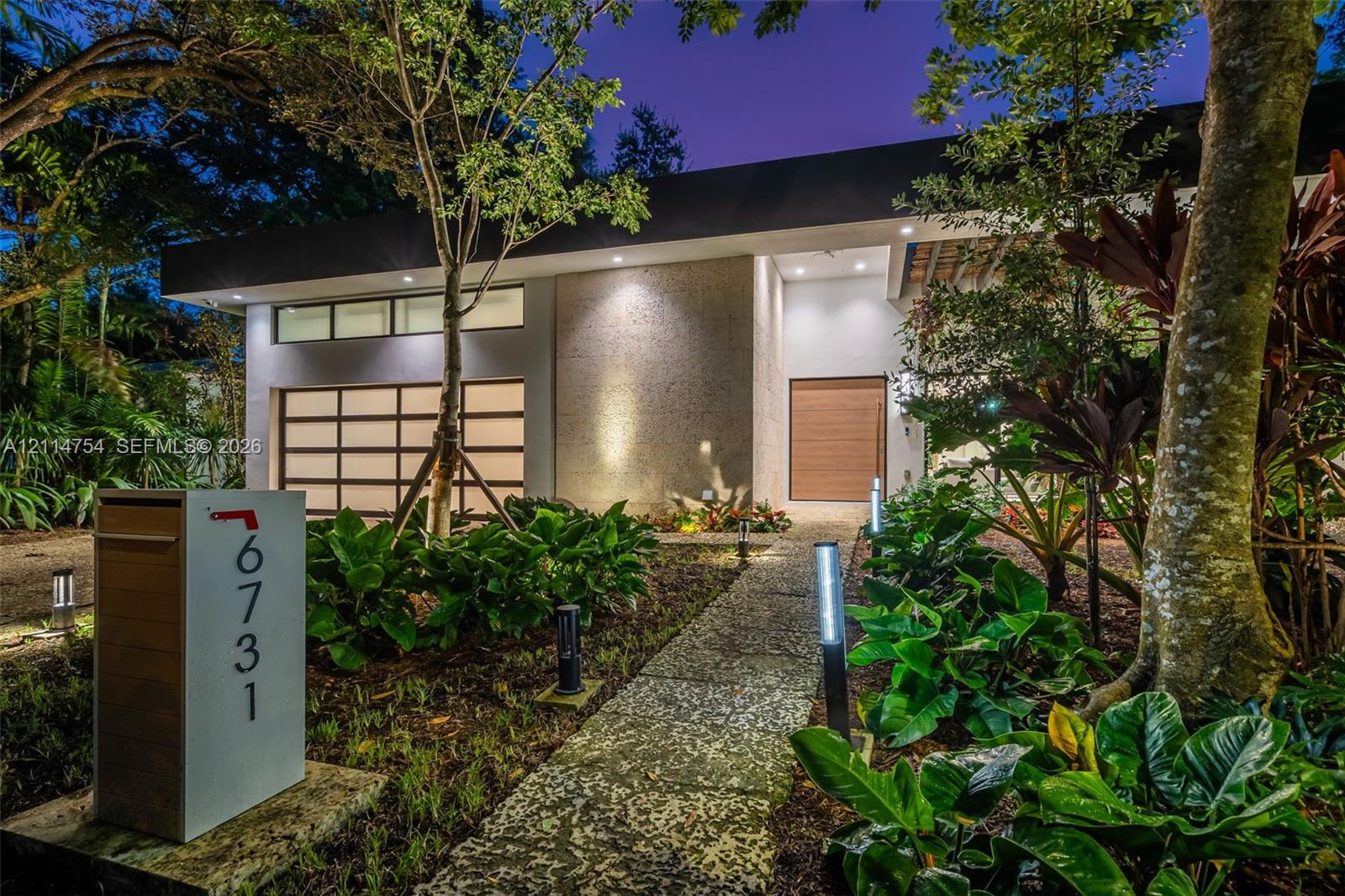 Contemporary exterior featuring a textured stone facade, a multi-pane frosted glass garage door, clerestory windows, and a pergola-covered entry