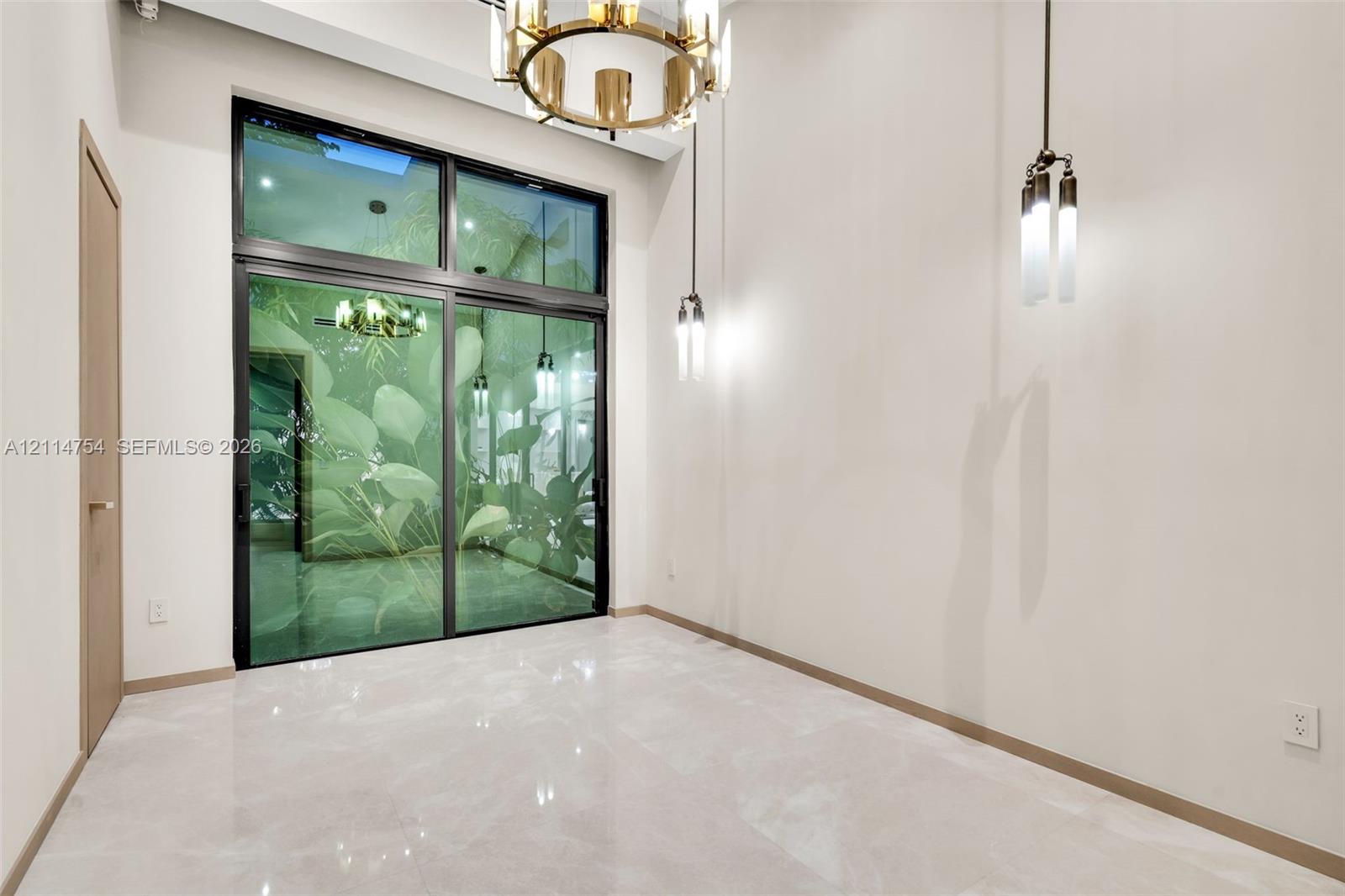 Vaulted ceilings featuring multi-pendant spherical lighting, light-toned wood-finish interior doors, and large-format neutral tile flooring