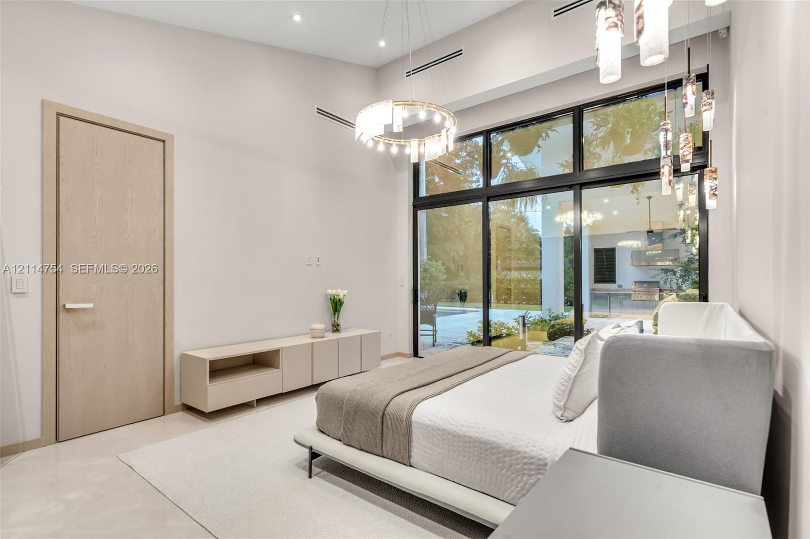 Vaulted ceilings featuring a circular crystal chandelier, recessed lighting, floor-to-ceiling black-framed windows, and built-in matte finish cabinetry