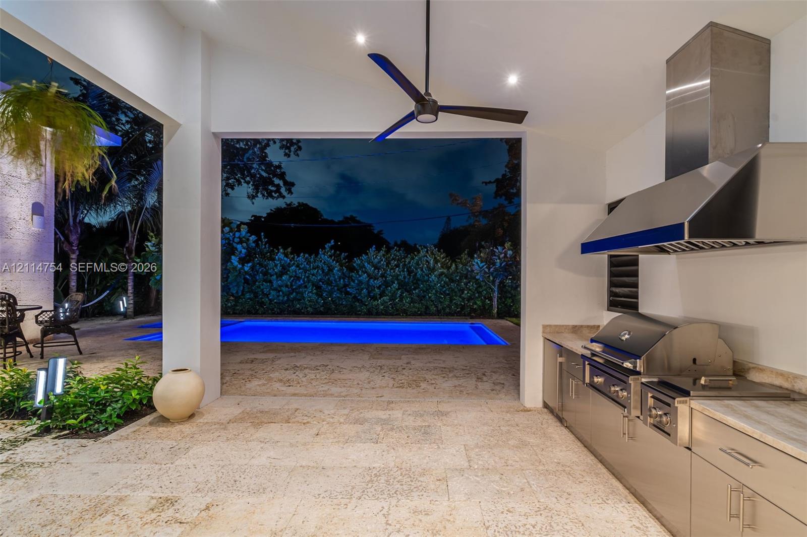 Modern contemporary facade featuring a textured stone accent wall, natural wood-finish front door, horizontal-pane garage door, overhead beam detailing, and clerestory windows