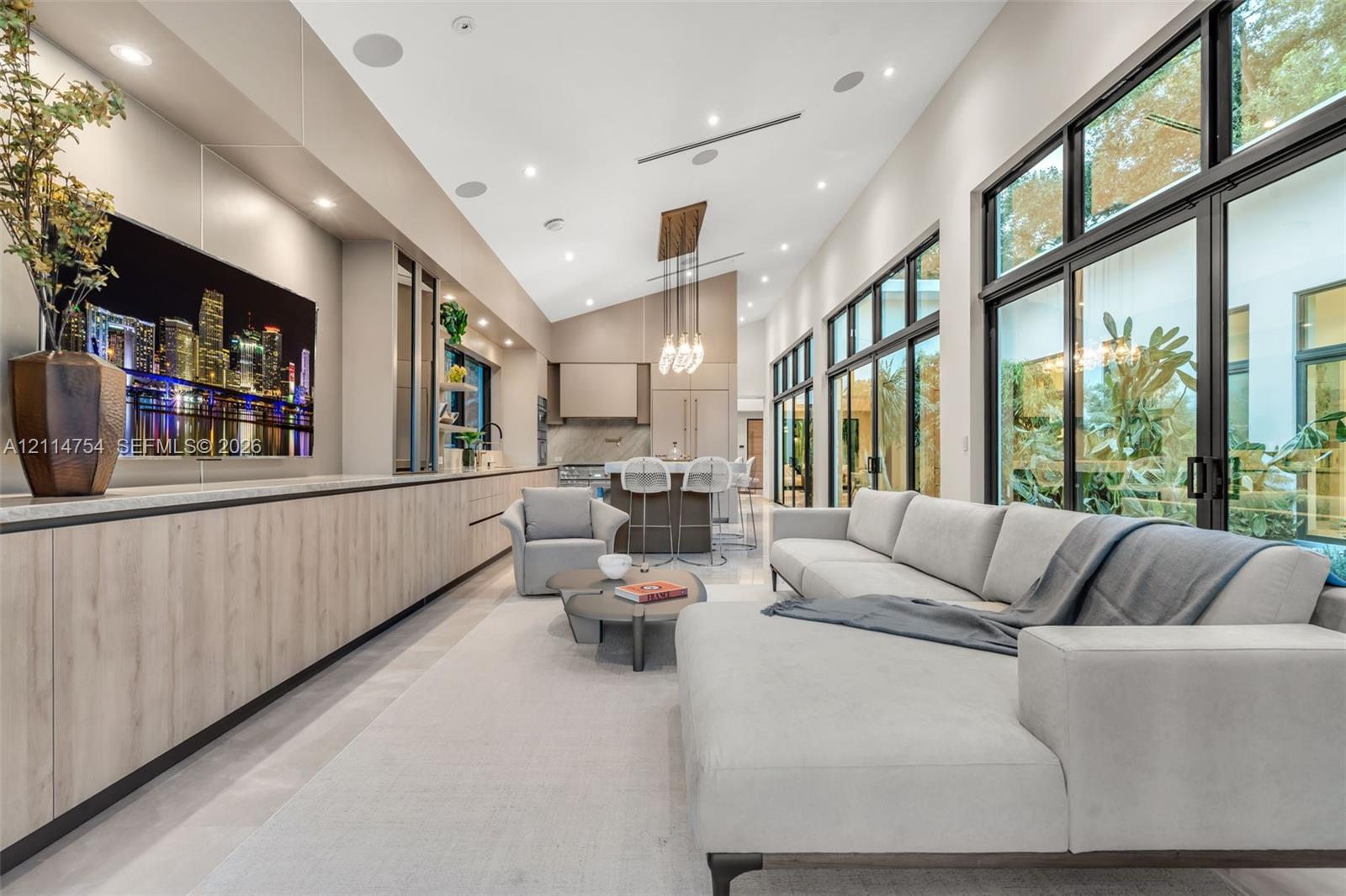 Vaulted ceilings, expansive glass sliding doors, built-in floor-to-ceiling cabinetry, recessed lighting, and large-format tile flooring