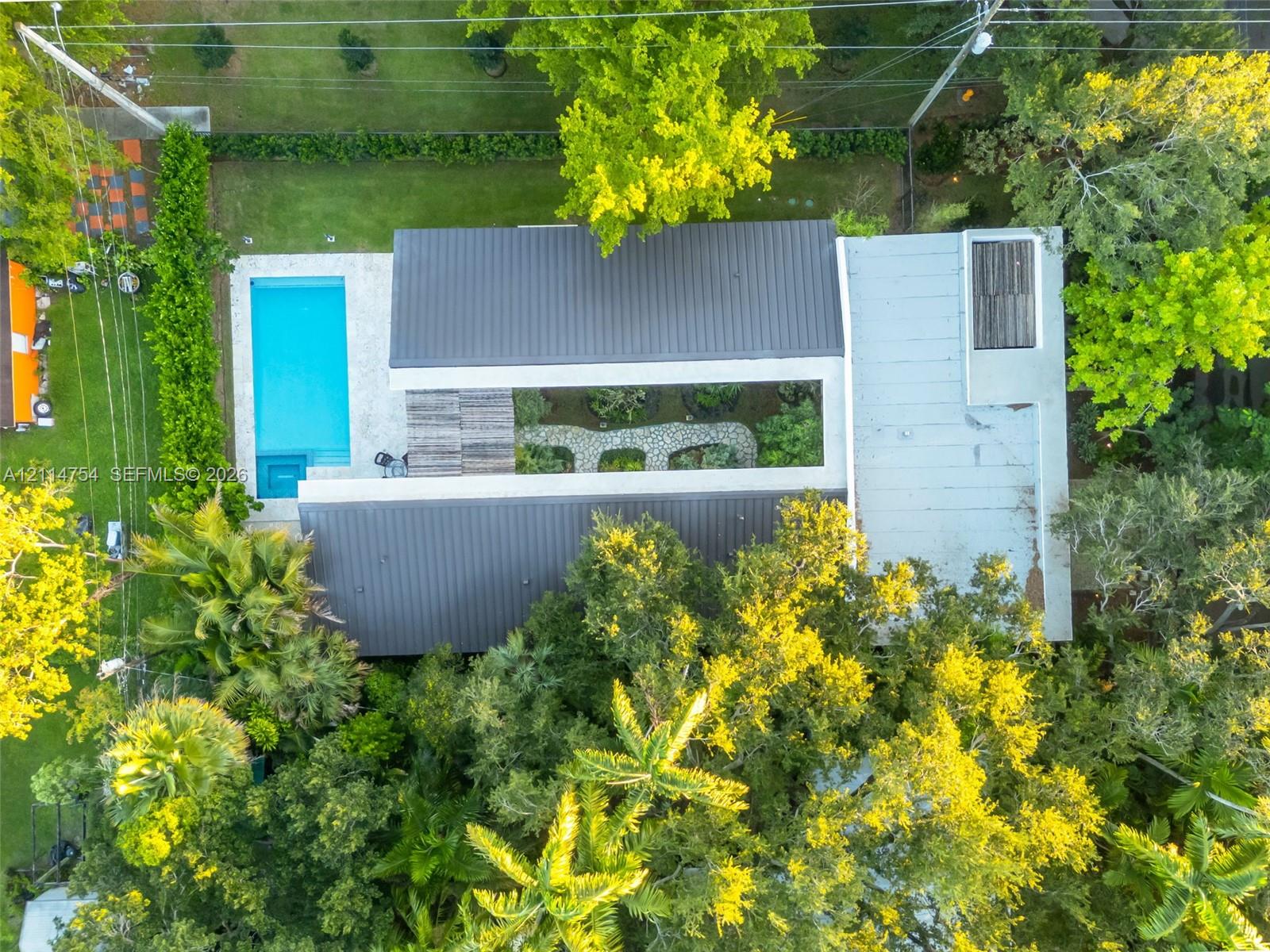 Aerial perspective of a tree-lined residential area featuring dense canopy cover, established vegetation, and proximity to urban infrastructure