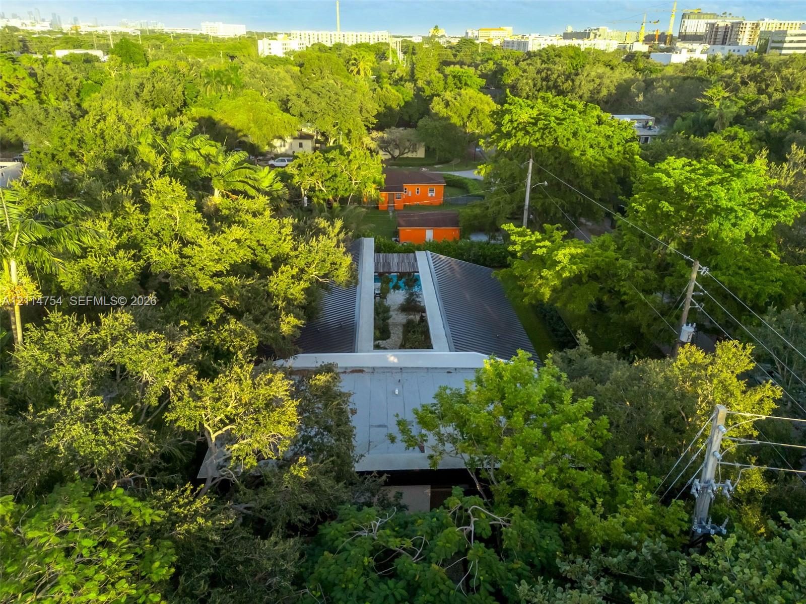 Aerial perspective featuring a metal roof structure, an integrated central courtyard, and dense mature canopy coverage