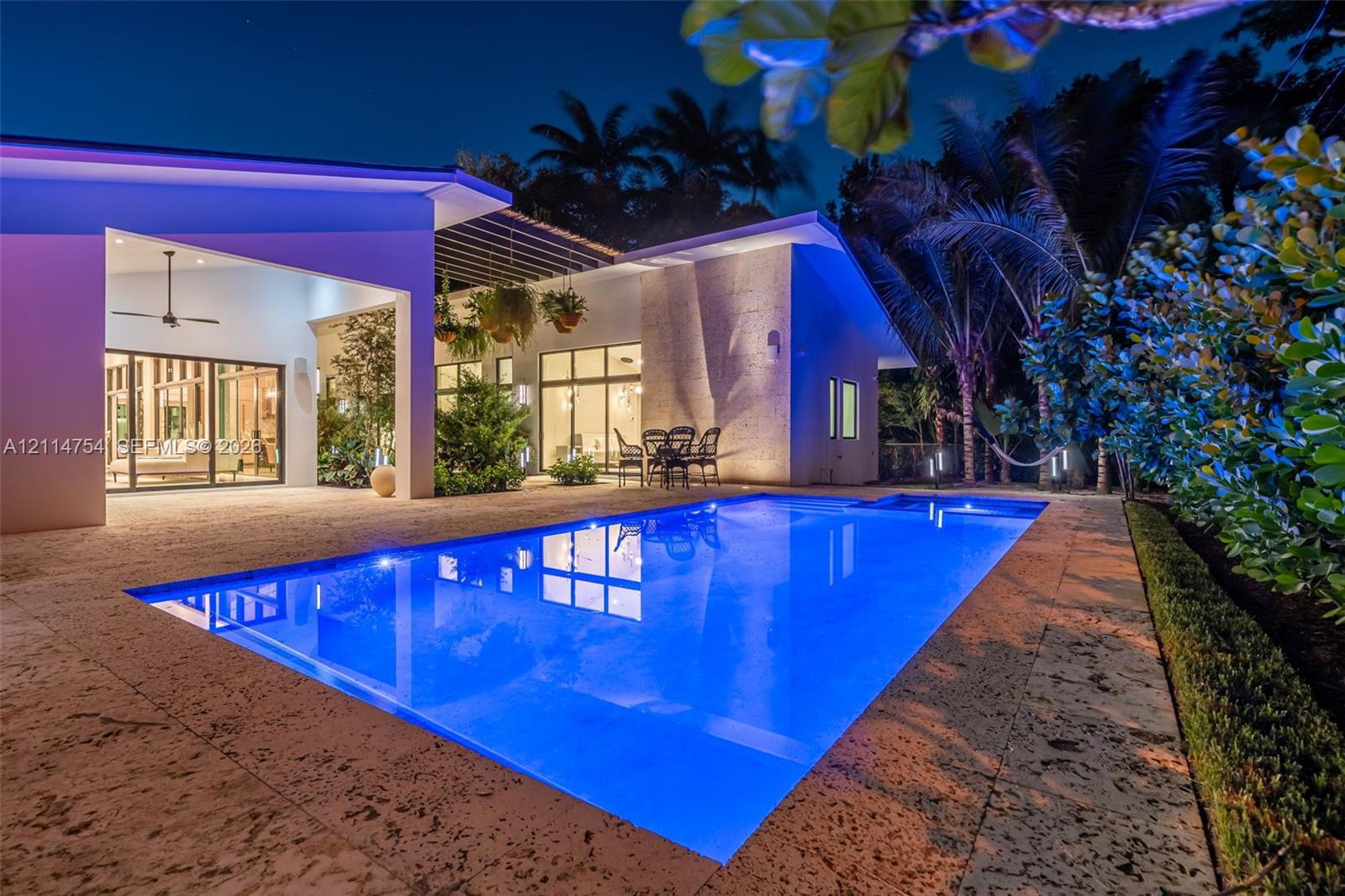 Outdoor kitchen featuring stainless steel cabinetry, integrated grill, and a professional-grade range hood, complemented by stone flooring and an in-ground swimming pool