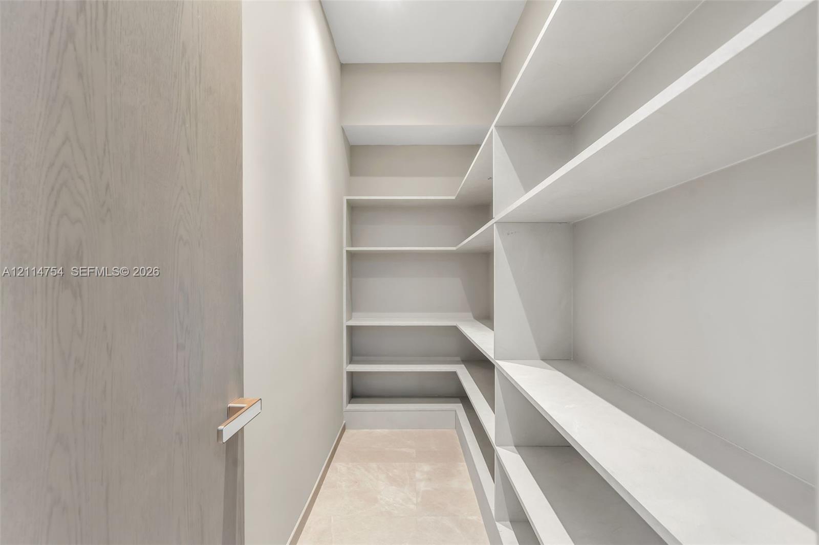 Vaulted ceilings, large-scale crystal chandelier, built-in cabinetry with light wood finish, stone-finish flooring, and floor-to-ceiling glass wall panels