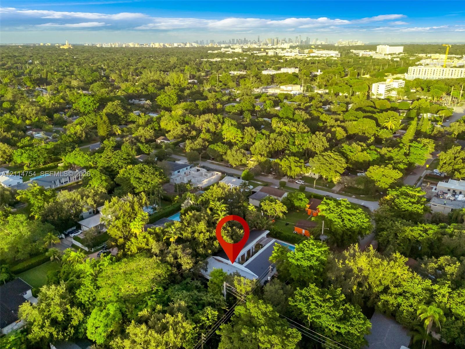 Aerial perspective of property featuring dense mature tree canopy, integrated paved central courtyard, and dark-toned metal roofing