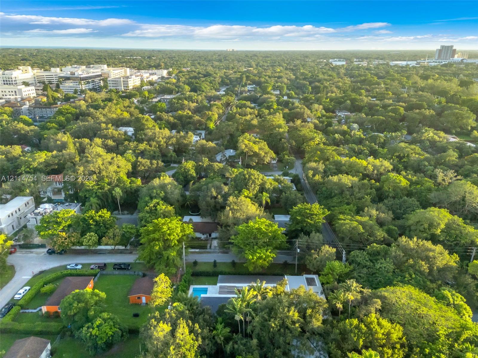 Aerial perspective of a contemporary residence featuring a flat roofline, a private rectangular pool, and extensive mature landscaping