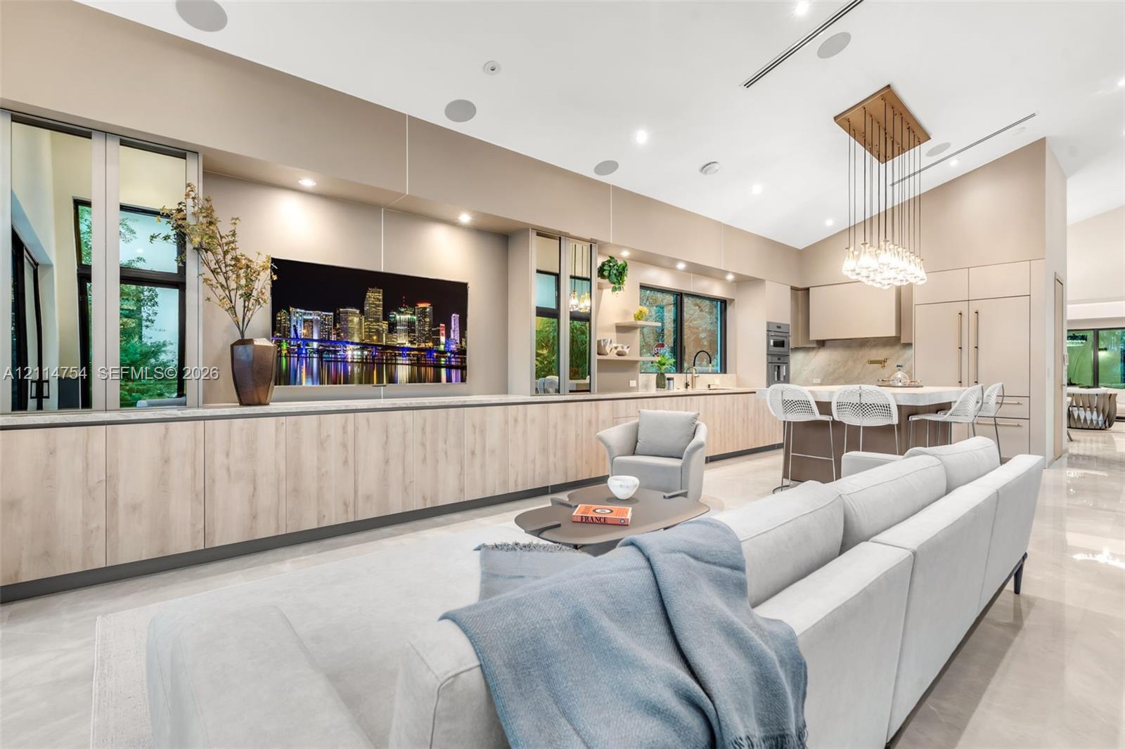 Chefs kitchen featuring a large stone-topped island, floor-to-ceiling glass sliding doors, recessed lighting, multi-bulb pendant lighting, and built-in stainless steel appliances