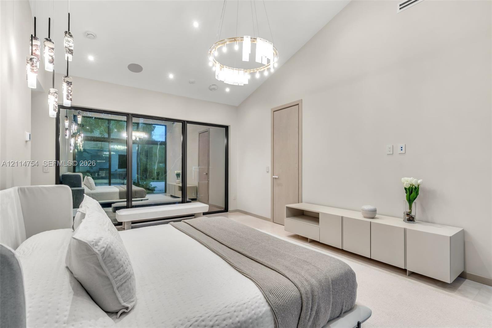 Stone tile wall and floor surfaces, glass-enclosed walk-in shower with gold-tone fixtures, freestanding soaking tub with floor-mounted faucet, and custom crystal chandelier