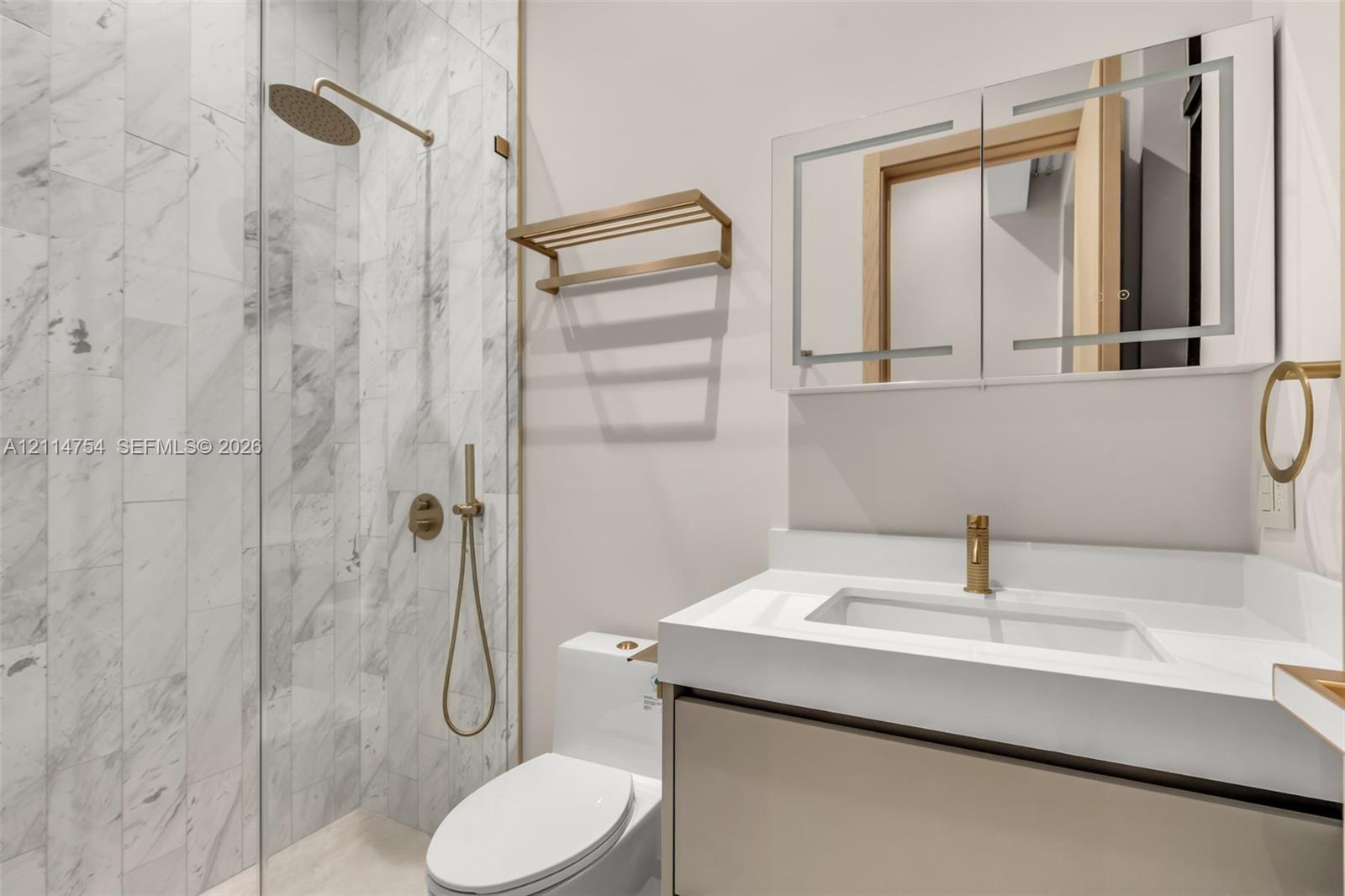 High-ceilinged room featuring large, floor-to-ceiling glass sliding doors, polished stone-finish flooring, recessed ceiling lighting, and a neutral color palette