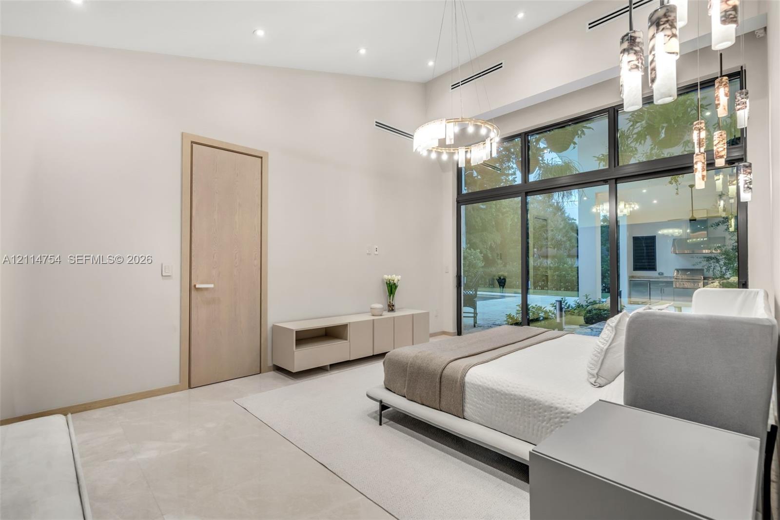 Foyer featuring large-format light-toned tile flooring, recessed ceiling lighting, a recessed tray ceiling, a large wood-finish door, and glass-paneled entry walls with black metal frames