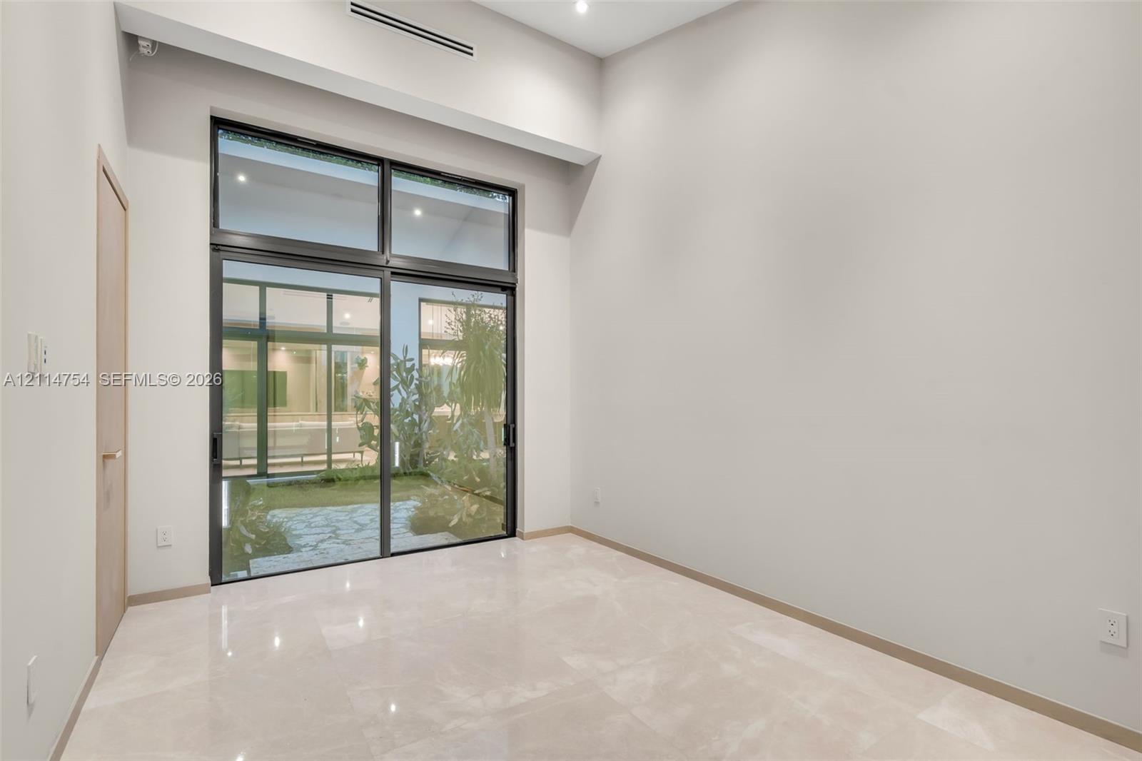 Vaulted ceilings featuring multi-tiered circular and drop-pendant lighting fixtures, floor-to-ceiling glass sliding doors, and light-toned hard-surface flooring