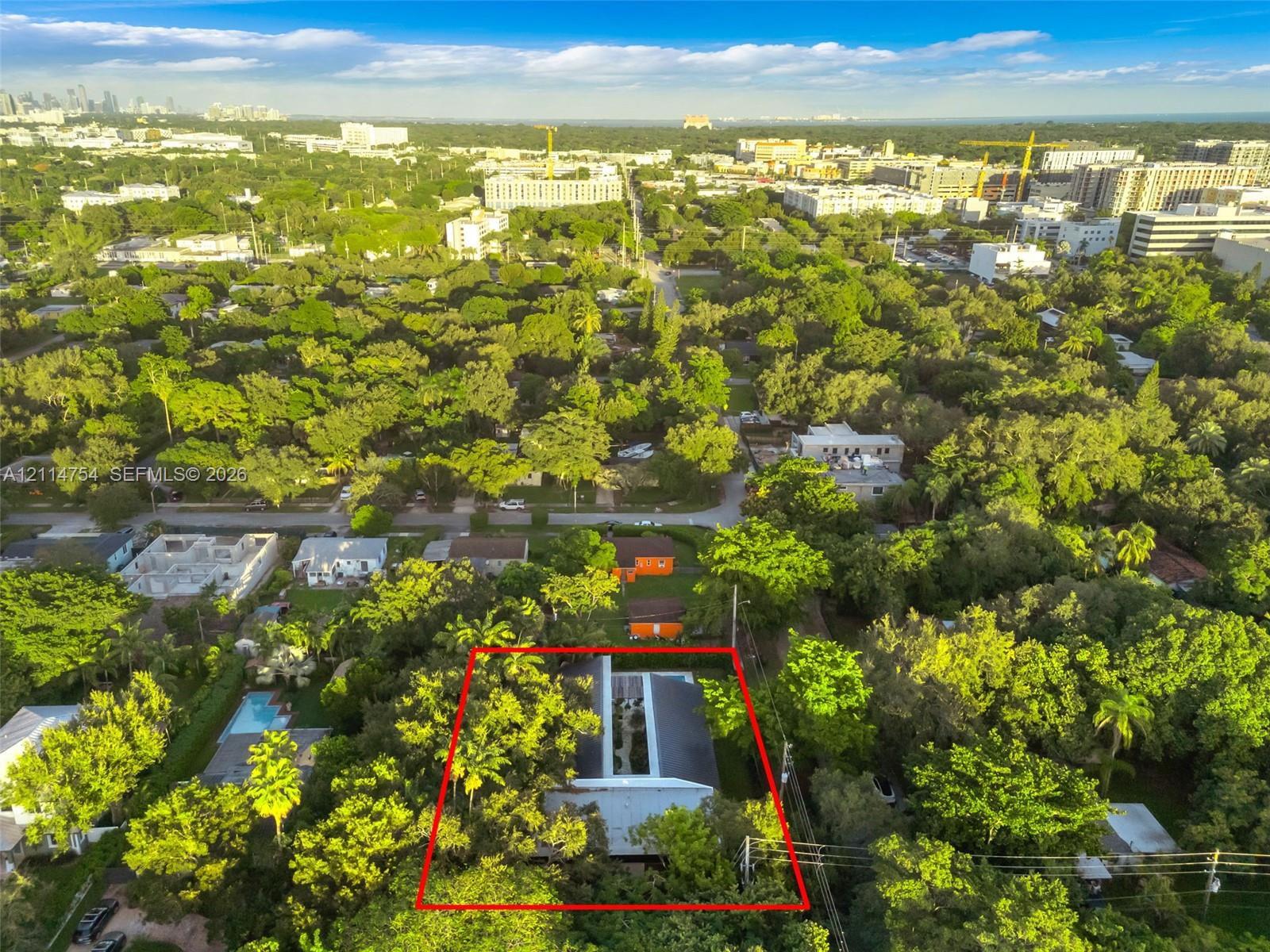 Aerial perspective featuring a metal roof structure, an integrated central courtyard, and dense mature canopy coverage