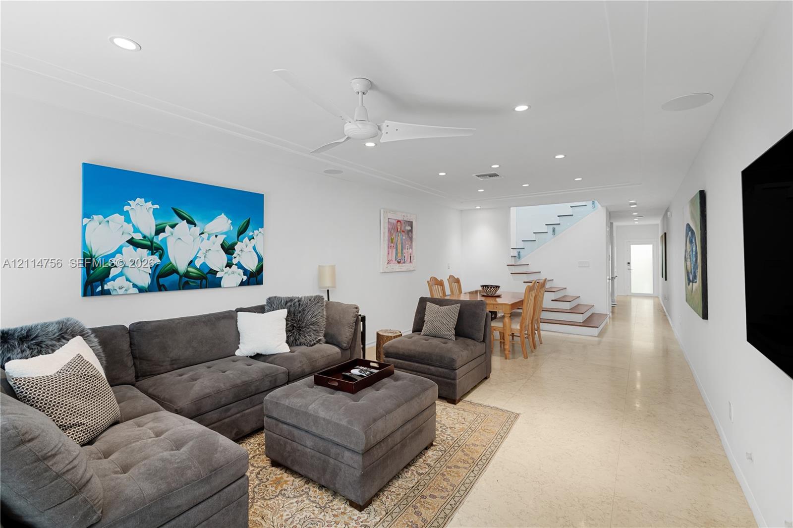 Open-concept space featuring polished stone flooring, recessed lighting, a modern ceiling fan, and a staircase with glass railings