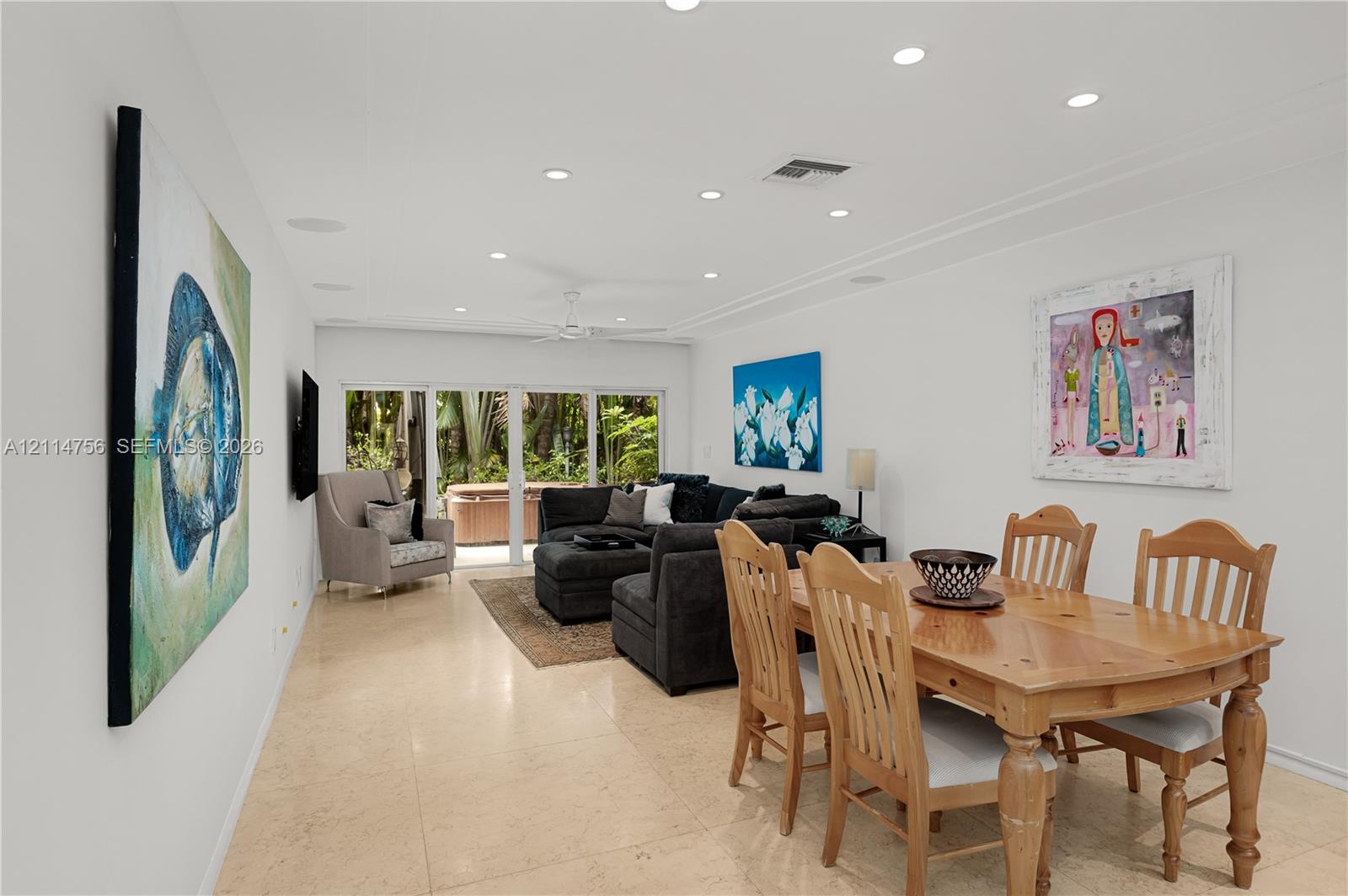 Open-concept interior featuring recessed lighting, smooth finish ceiling, neutral stone-finish tile flooring, and floor-to-ceiling glass sliding doors Open-concept interior featuring recessed lighting, smooth finish ceiling, neutral stone-finish tile flooring, and floor-to-ceiling glass sliding doors