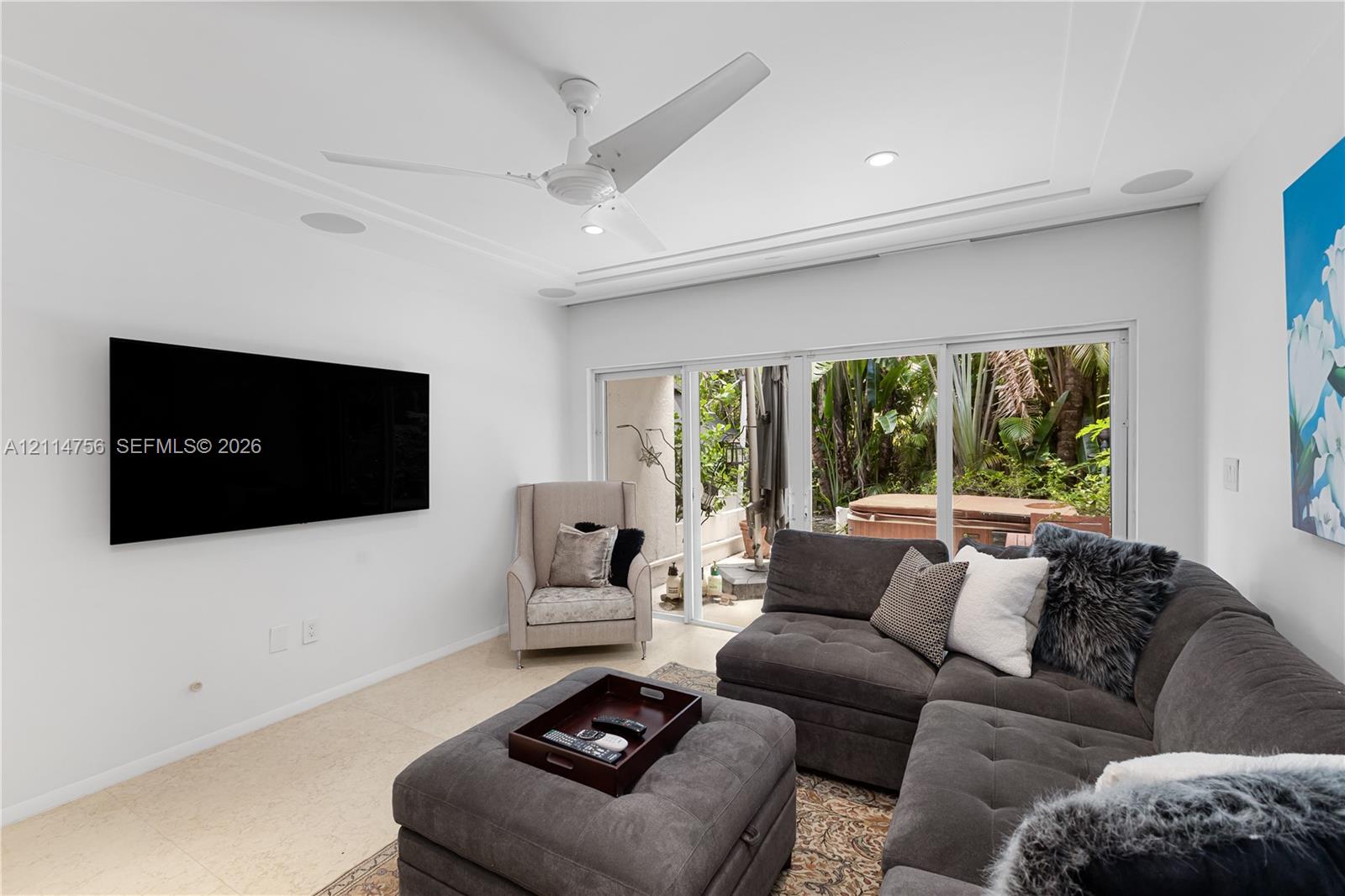 Living area featuring recessed lighting, a modern ceiling fan, stone flooring, and expansive sliding glass doors Living area featuring recessed lighting, a modern ceiling fan, stone flooring, and expansive sliding glass doors