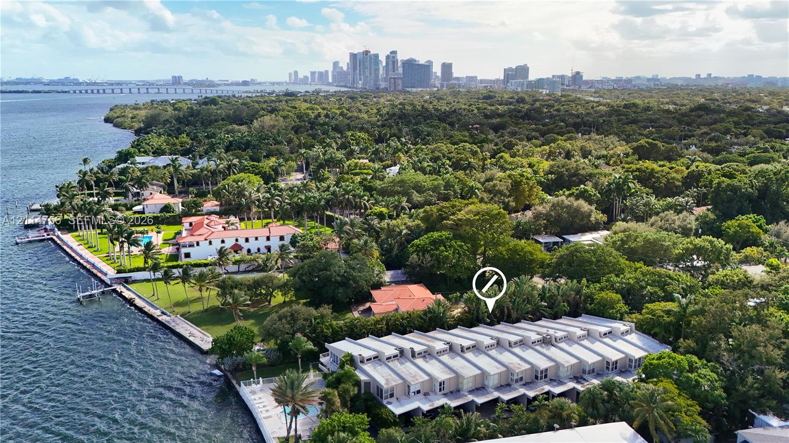 Waterfront property featuring a seawall, expansive lawn, mature landscaping, and proximity to city skyline Waterfront property featuring a seawall, expansive lawn, mature landscaping, and proximity to city skyline