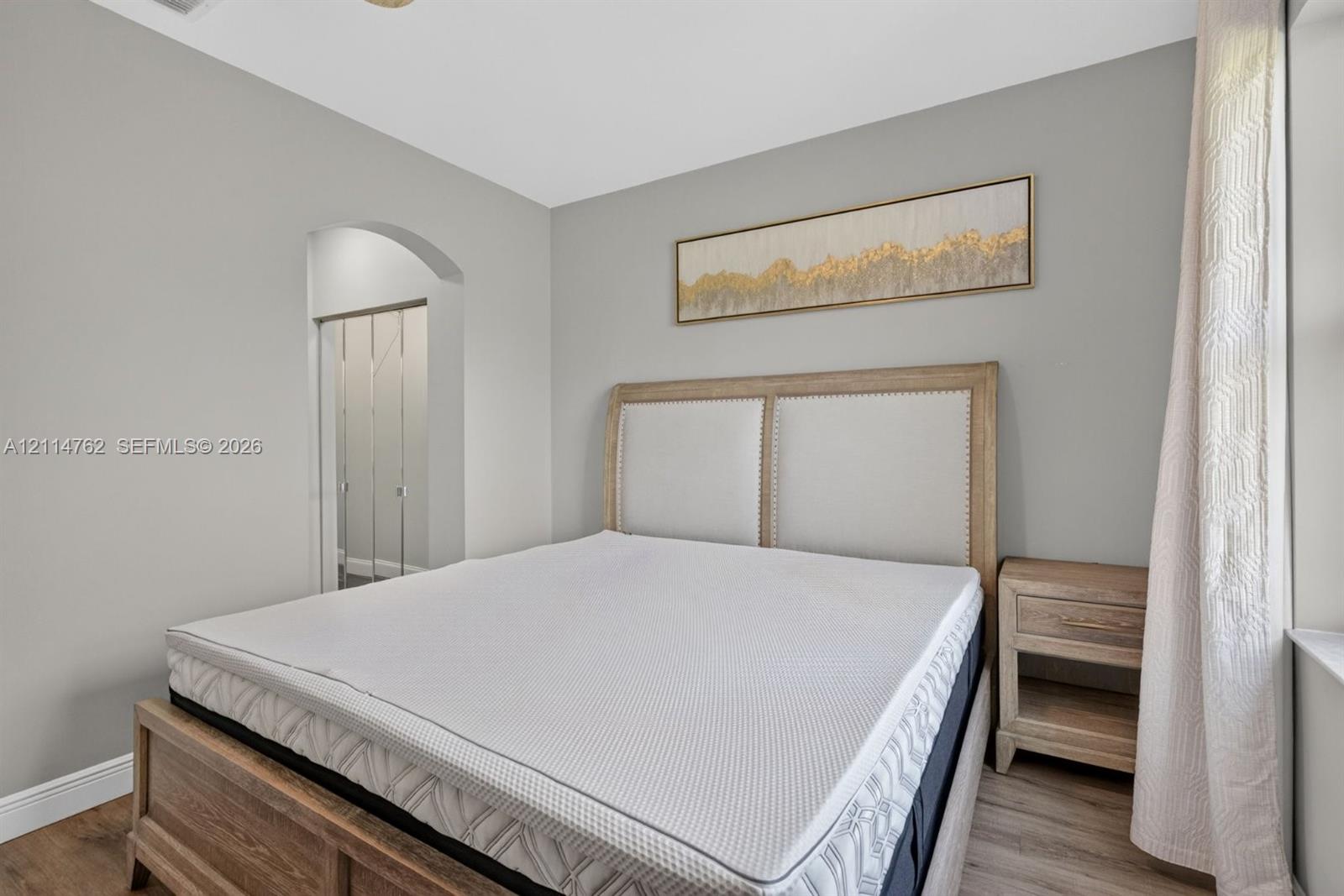 Neutral-toned walls featuring a structural arched entryway and wood-finish flooring