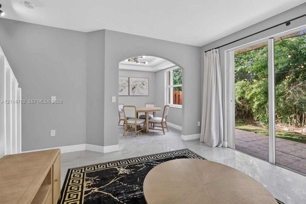 Large-format tile flooring, architectural arched threshold, and sliding glass doors with direct access to a paved patio