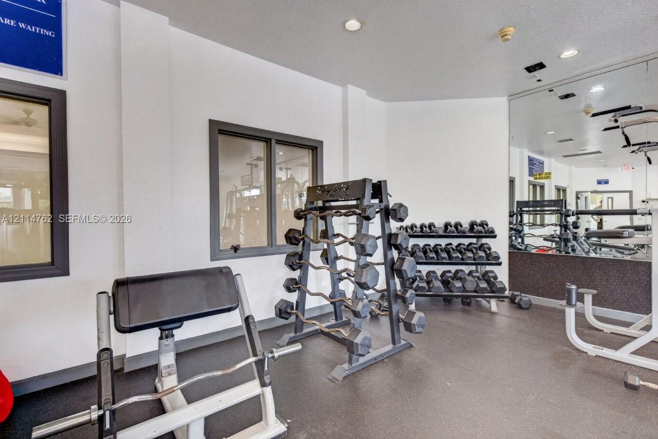 Fitness center featuring recessed lighting, a full-wall mirror, and rubberized flooring