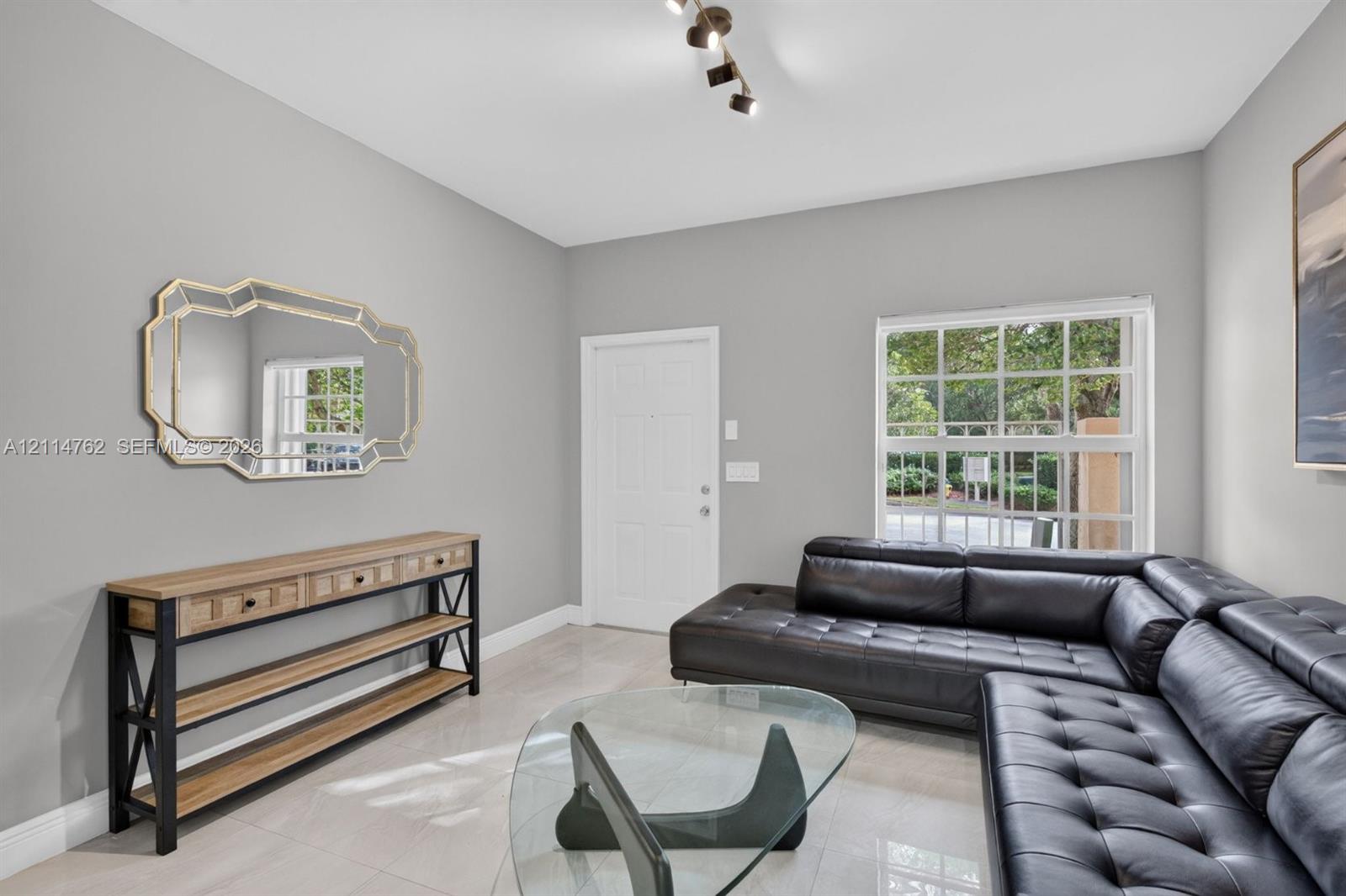 Neutral interior space featuring polished tile flooring, a multi-paned window, and a modern adjustable track lighting fixture