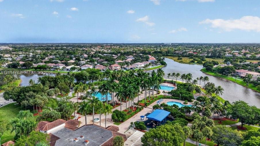 Community complex featuring multiple swimming pools, paved walkways, palm tree landscaping, and direct water frontage