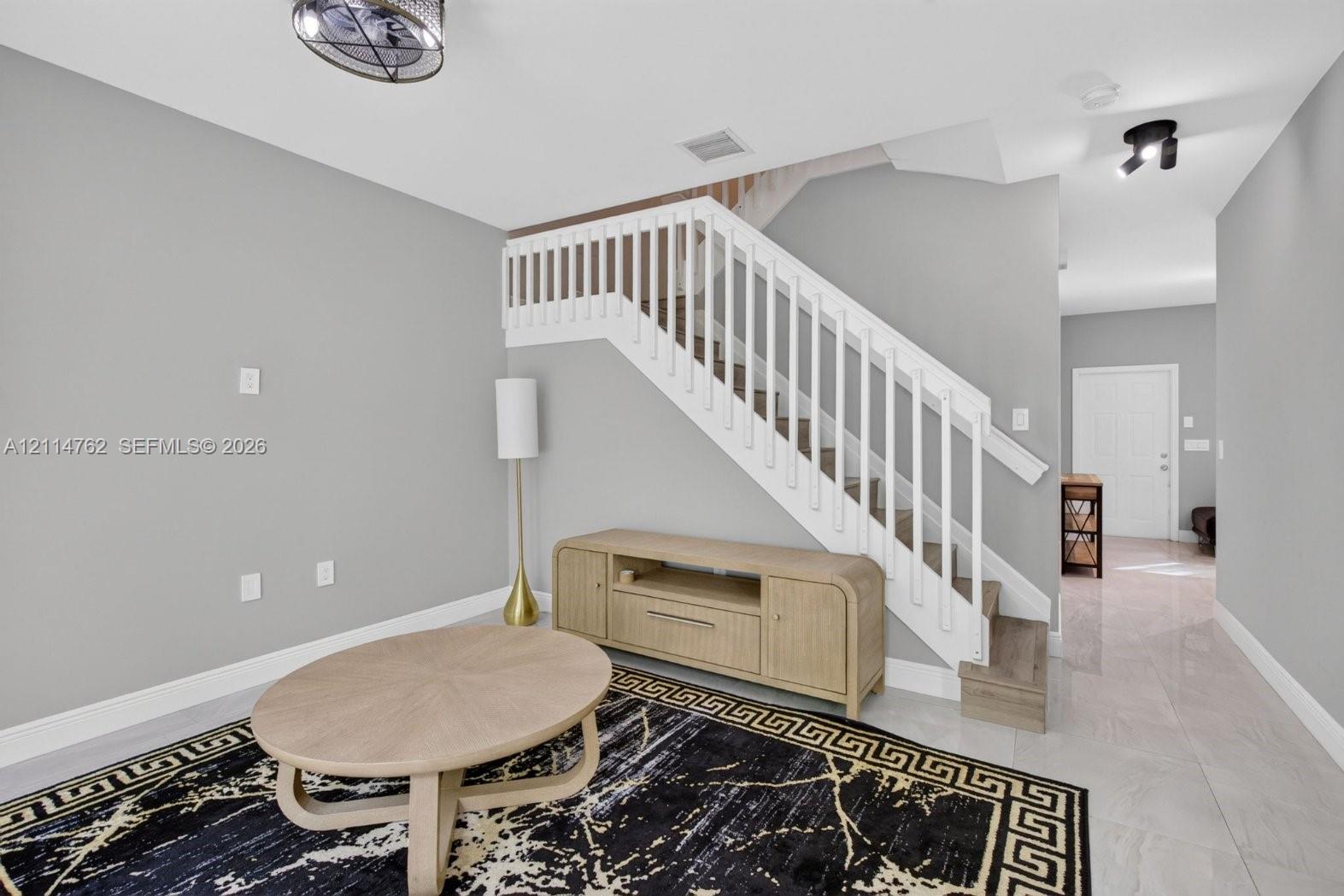Staircase featuring white balusters and wood-finish treads, complemented by neutral wall paint and polished tile flooring throughout