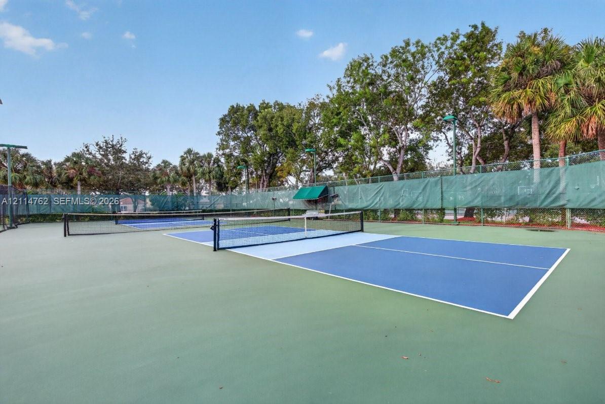 Dual pickleball courts featuring specialized athletic surfacing, high-visibility nets, perimeter mesh fencing, and mature perimeter landscaping