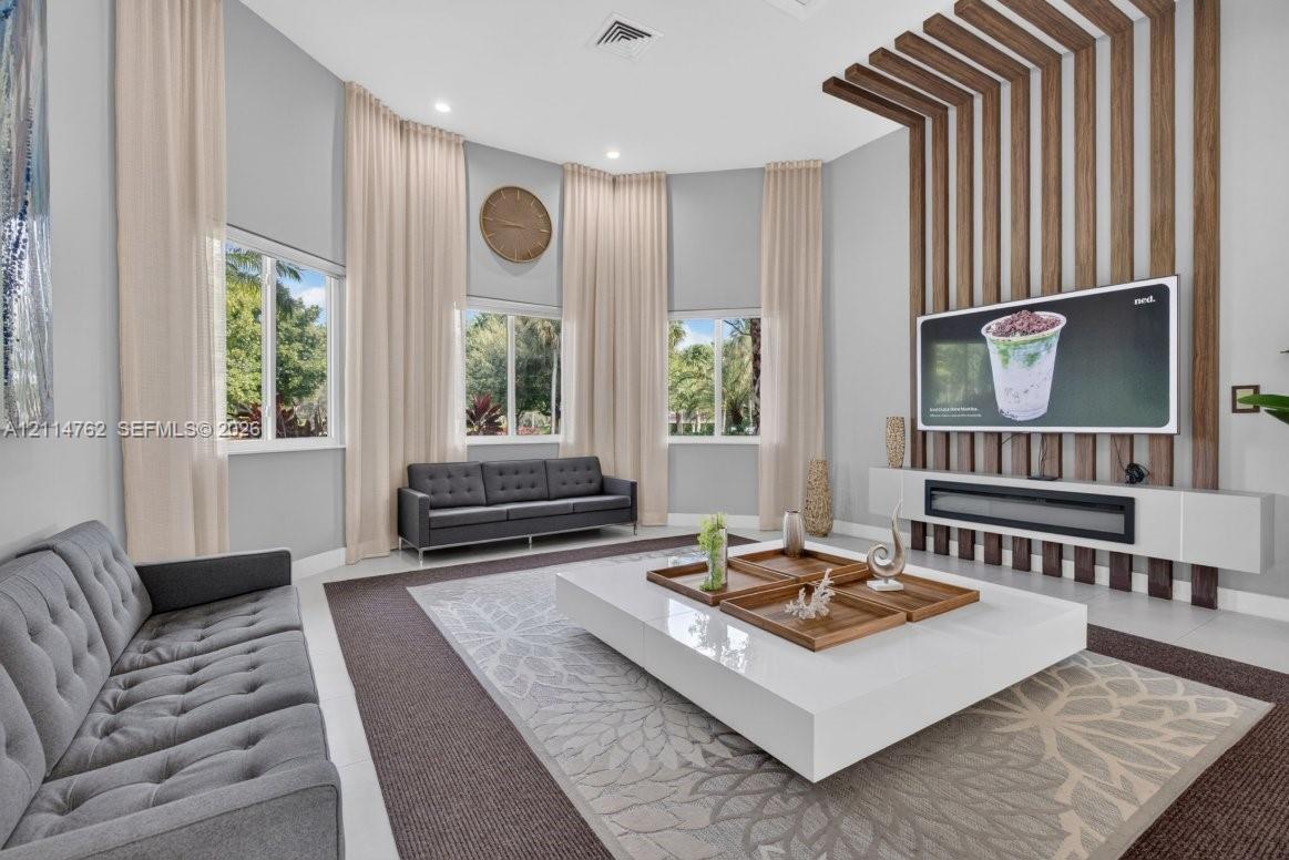 Vaulted ceilings, floor-to-ceiling wooden slat accent wall, integrated horizontal linear fireplace, and large windows with extensive drapery