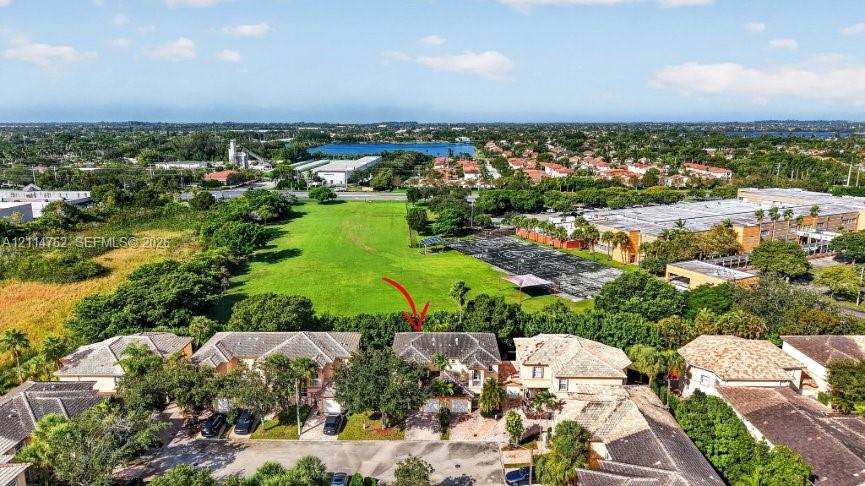 Aerial perspective featuring a multi-story residence with a pitched tile roof, attached multi-car garage, and direct proximity to expansive green space