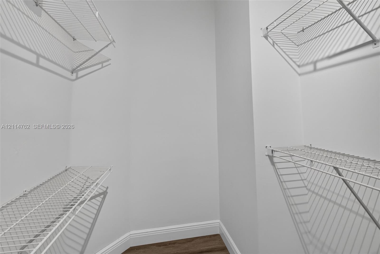 Storage area featuring white wire shelving units and wood-finish flooring