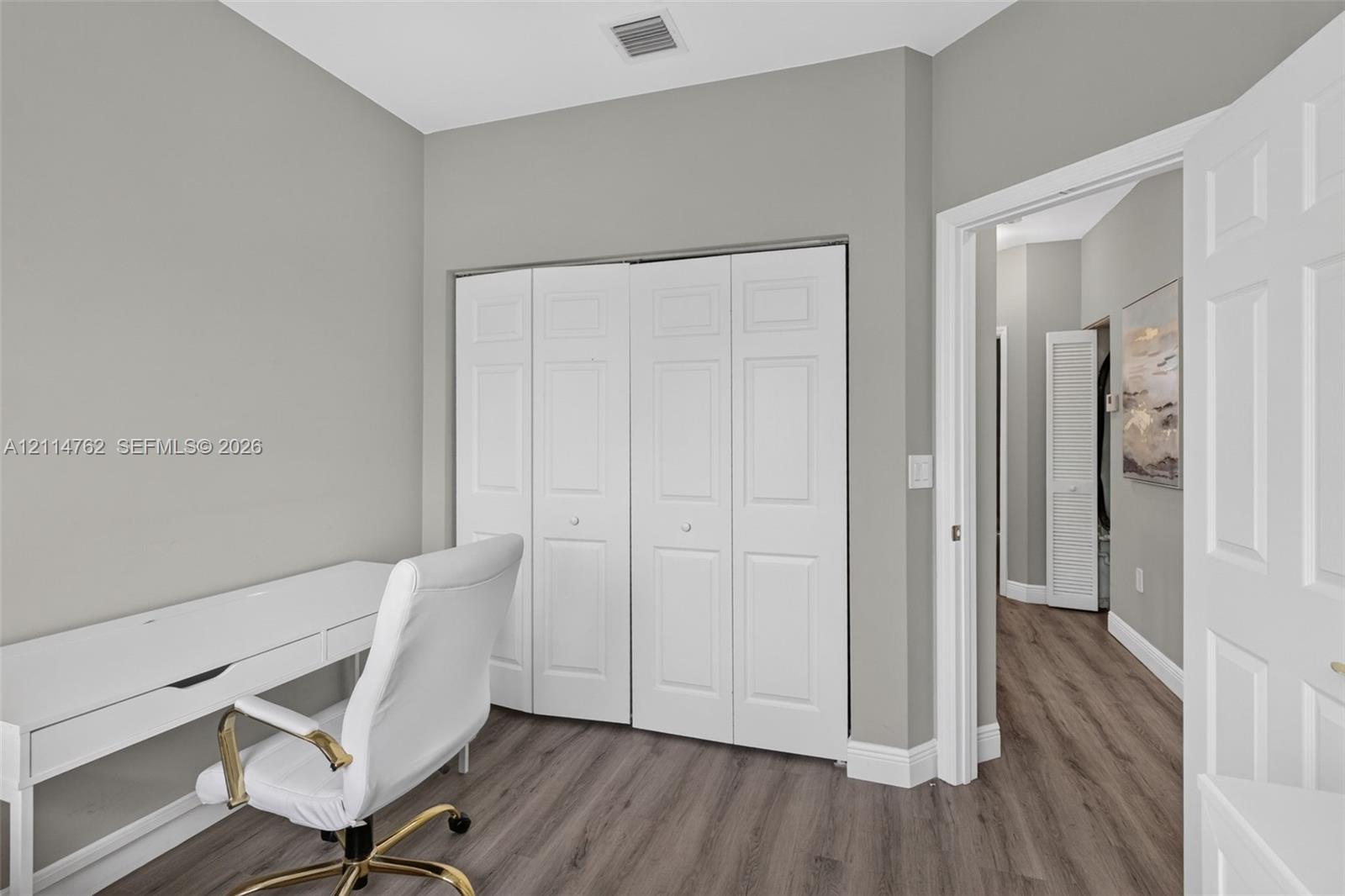Neutral-toned walls featuring wood-finish flooring and a white paneled closet door