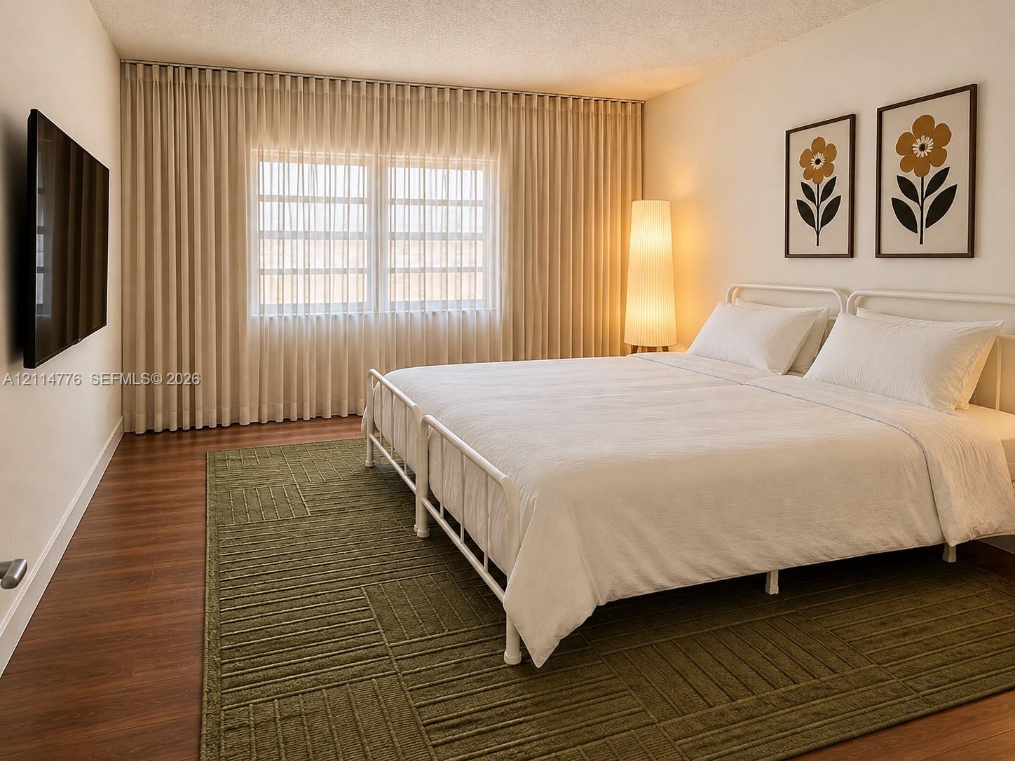 Wood-finish flooring, full-wall drapery, and a wall-mounted television