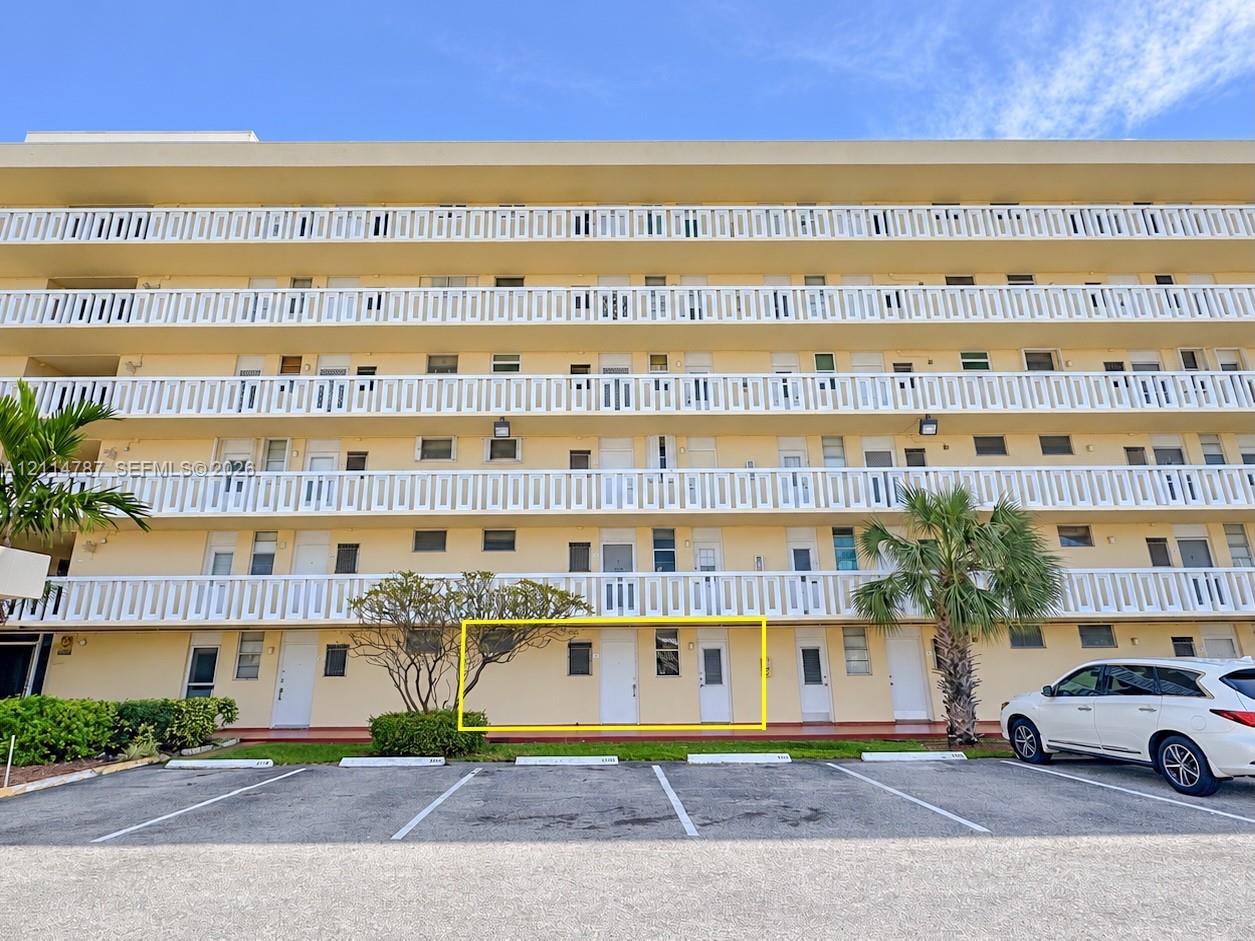 Multi-story residential building exterior featuring ground-level access, private entryway, and dedicated exterior parking space