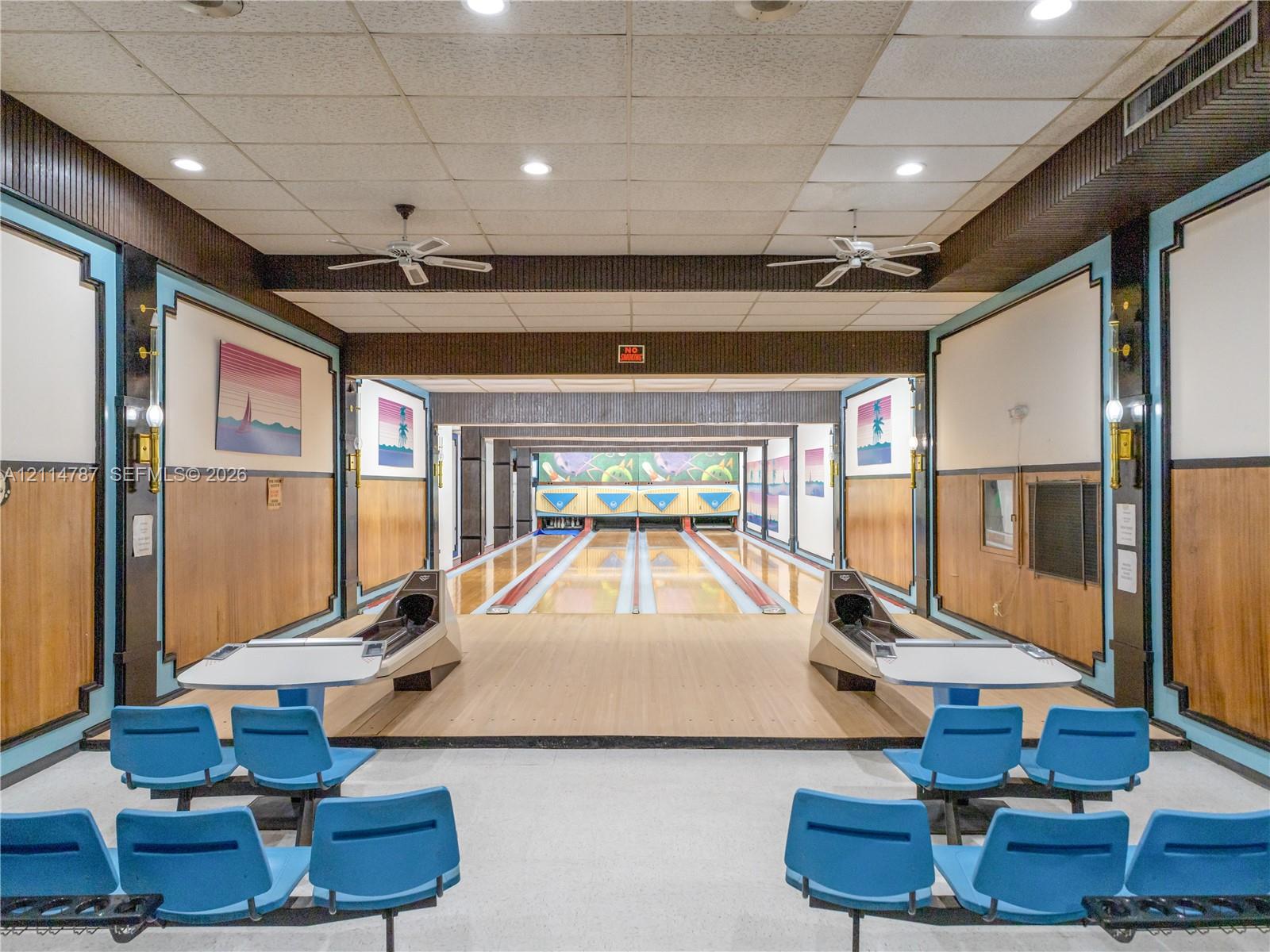 Indoor bowling alley featuring dual-lane hardwood synthetic surfaces, built-in ball returns, recessed ceiling lighting, and integrated wall-mounted sound-dampening panels