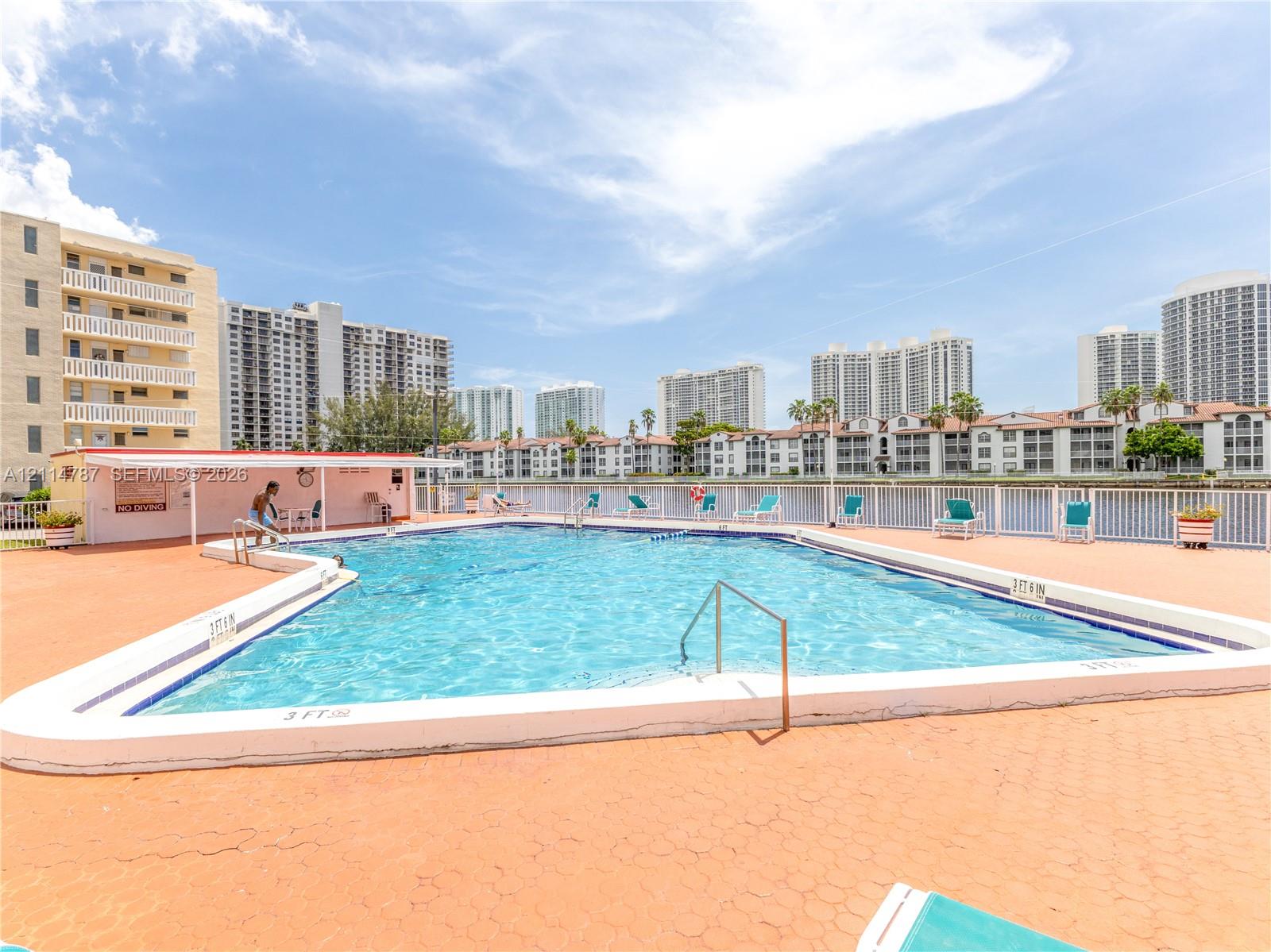 Outdoor swimming pool featuring a concrete deck, metal safety railing, and a covered shade structure